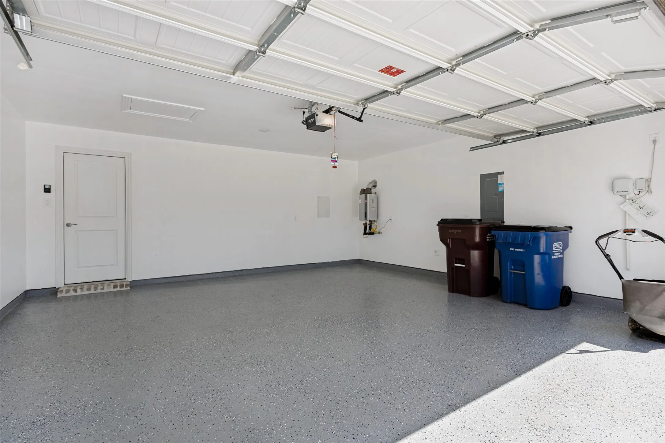 Garage featuring a finished floor, white walls, and a visible water heater