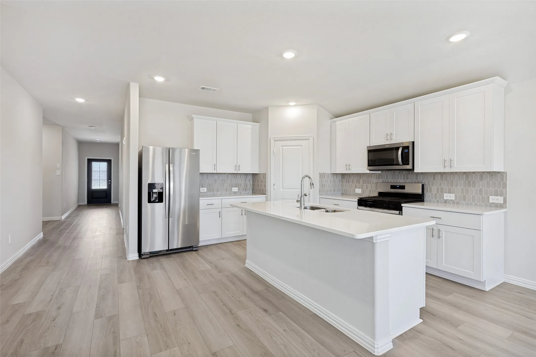 Kitchen featuring a central island, white cabinetry, stainless steel appliances, and wood-finish flooring