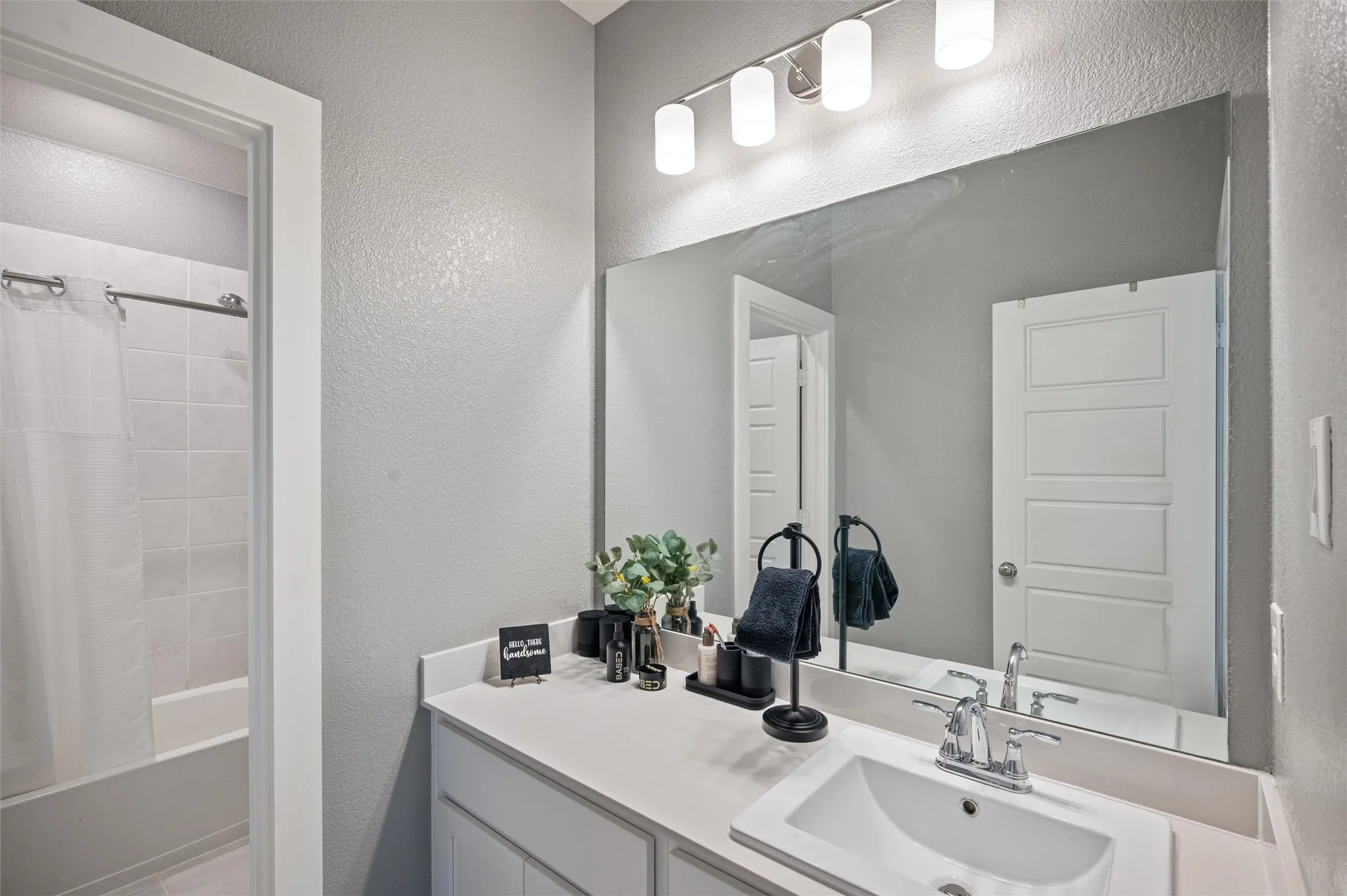 Bathroom vanity with an integrated sink, polished chrome faucet, and expansive wall mirror