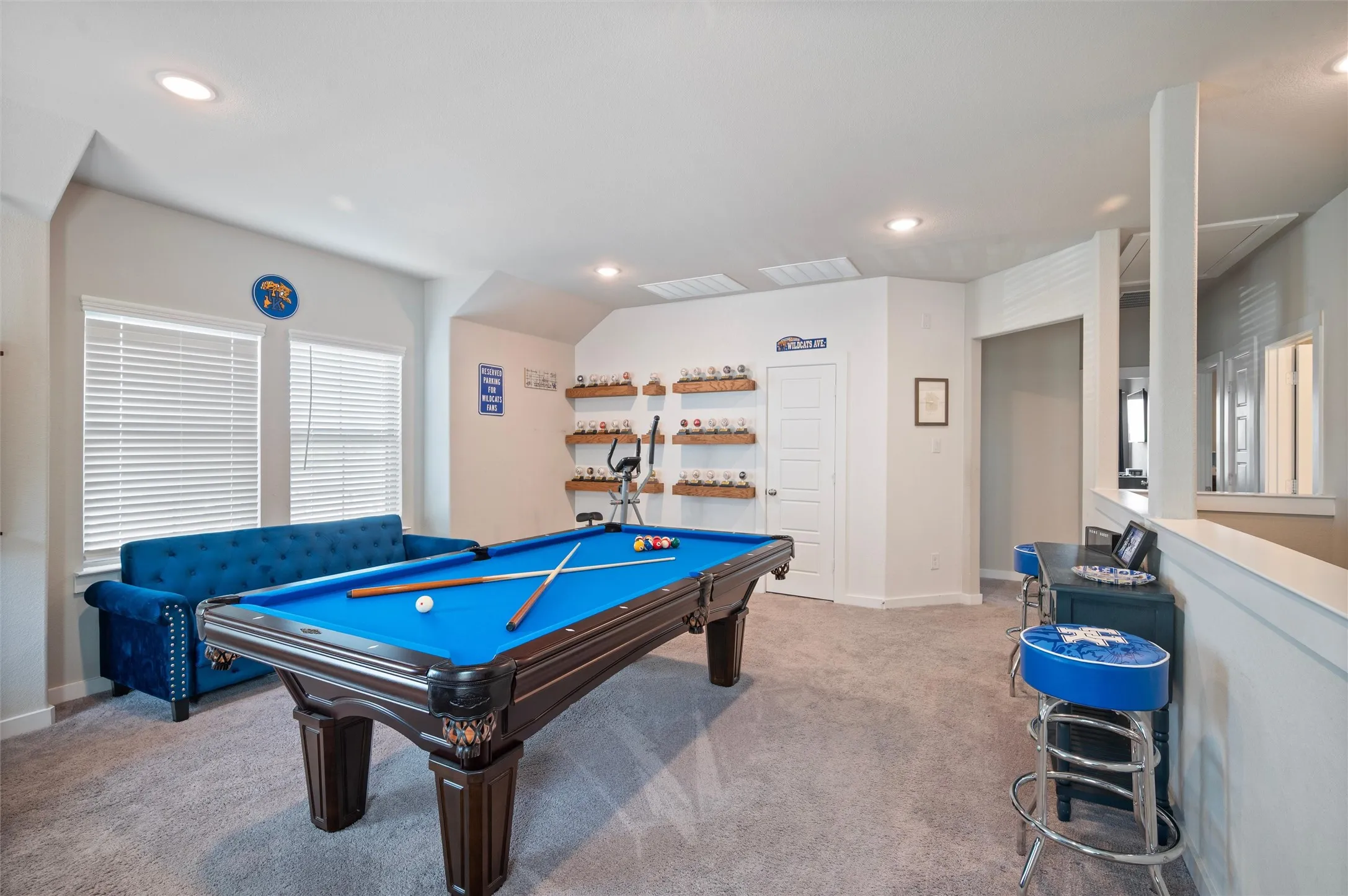 Spacious bonus room featuring recessed lighting, gray carpet flooring, two windows with blinds, and built-in shelving