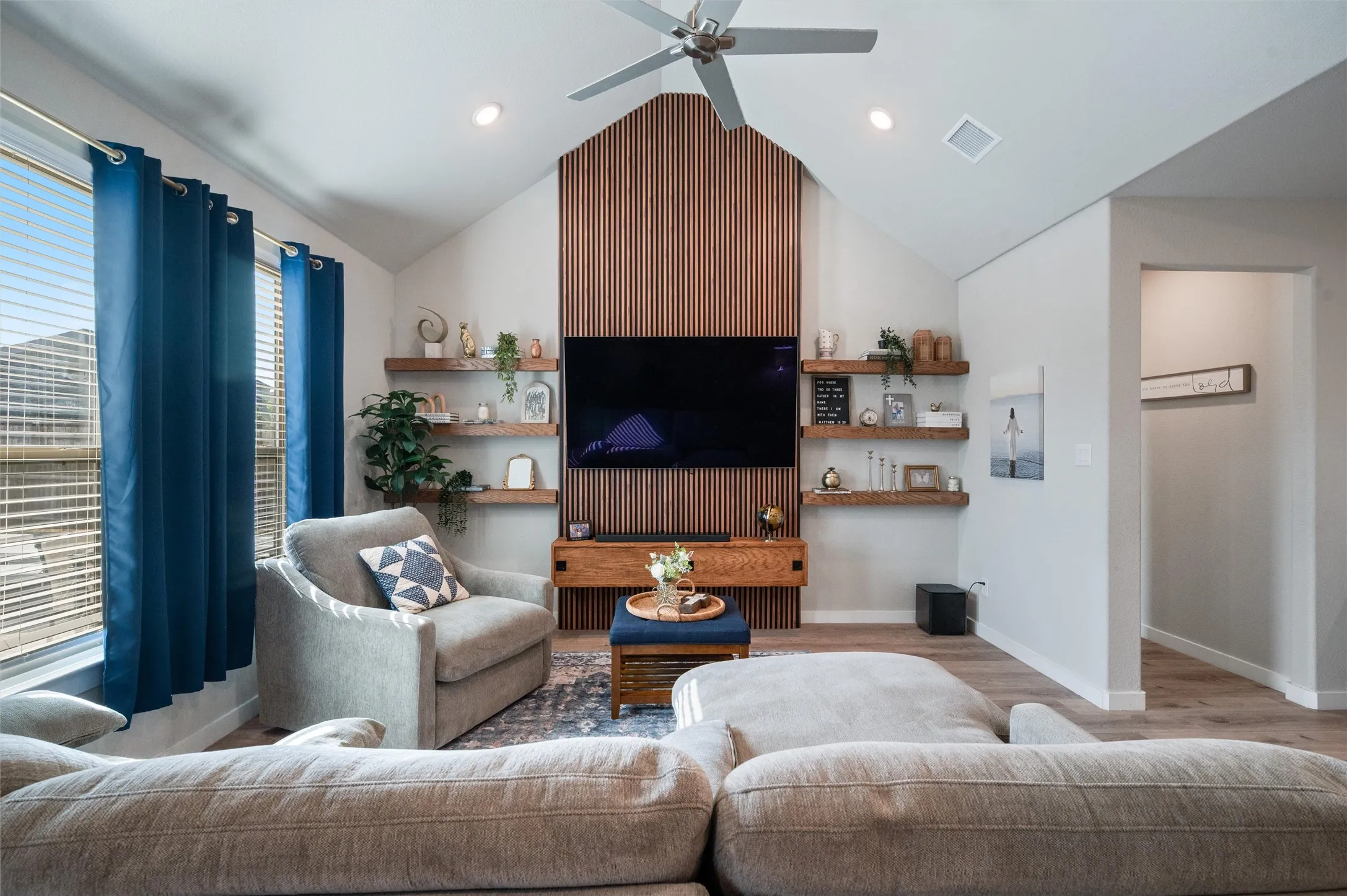 Vaulted ceiling with a ceiling fan, recessed lighting, wood-finish flooring, and a slat wood accent wall