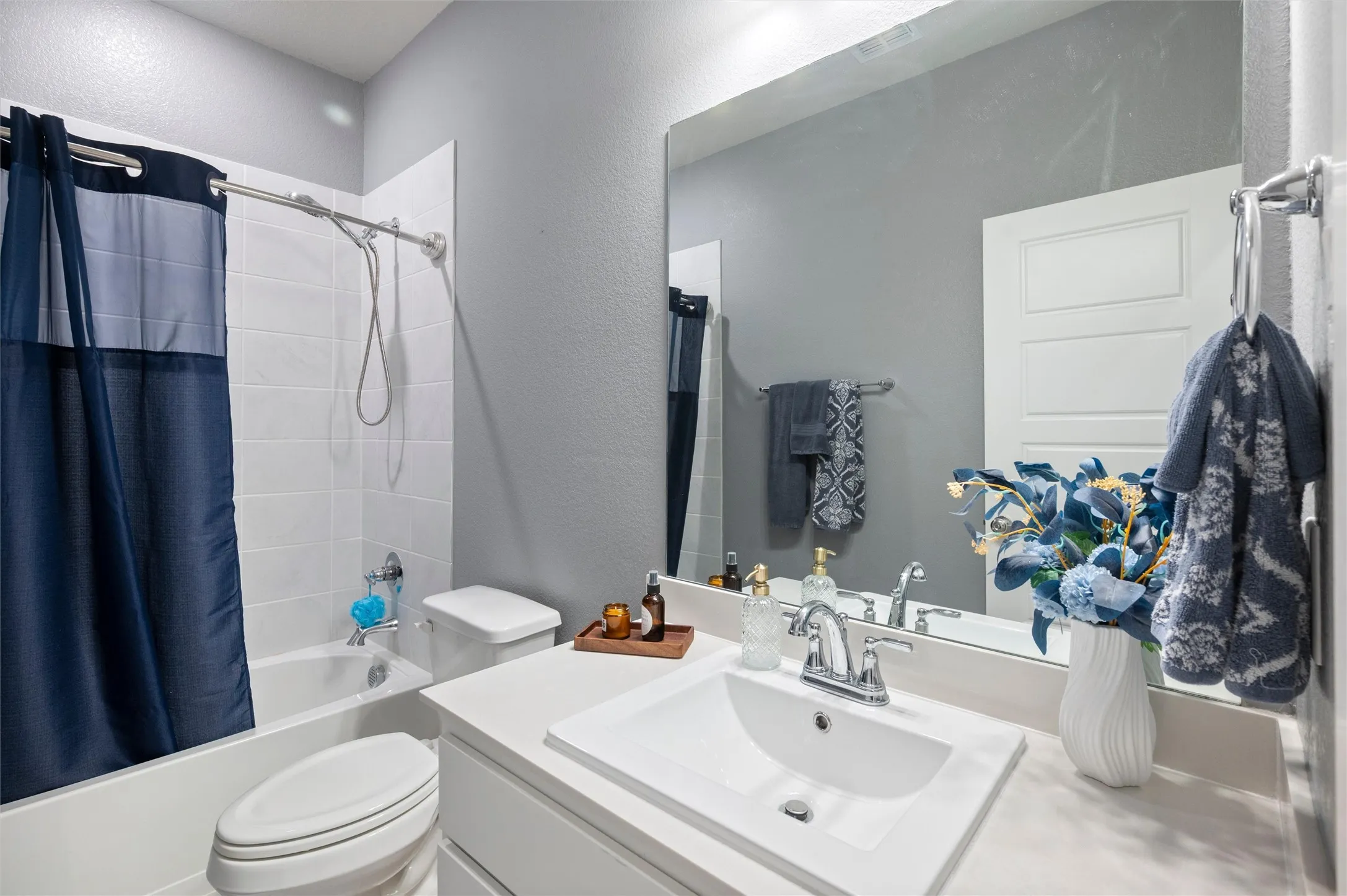 Bathroom featuring a tub/shower combination with white subway tile surround, white vanity with integrated sink, chrome faucet, and a large wall-mounted mirror