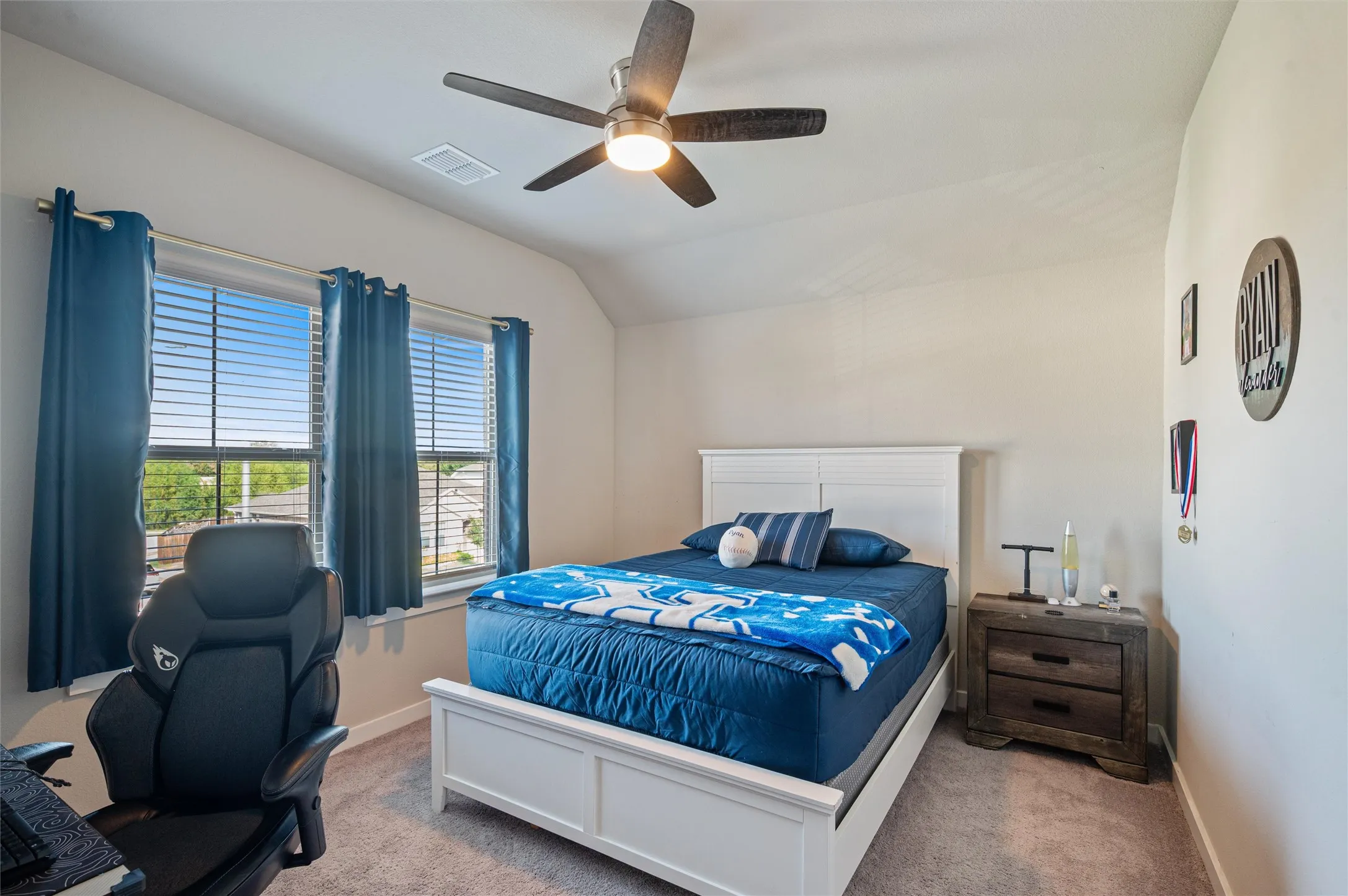 Neutral wall paint, plush carpeting, ceiling fan with integrated lighting, and dual windows with blinds