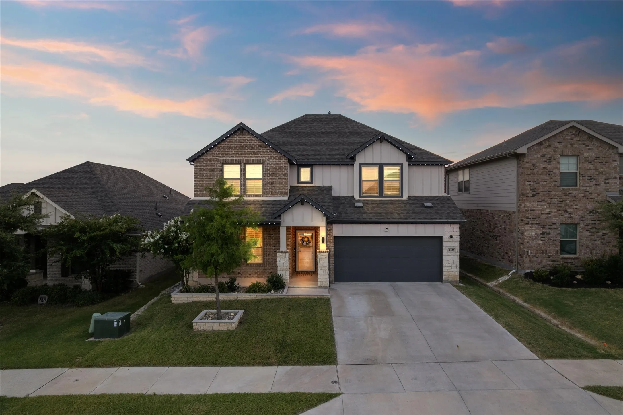 Two-story residence featuring a mixed-material facade with brick and siding, a dark asphalt shingle roof, an attached two-car garage, and a concrete driveway