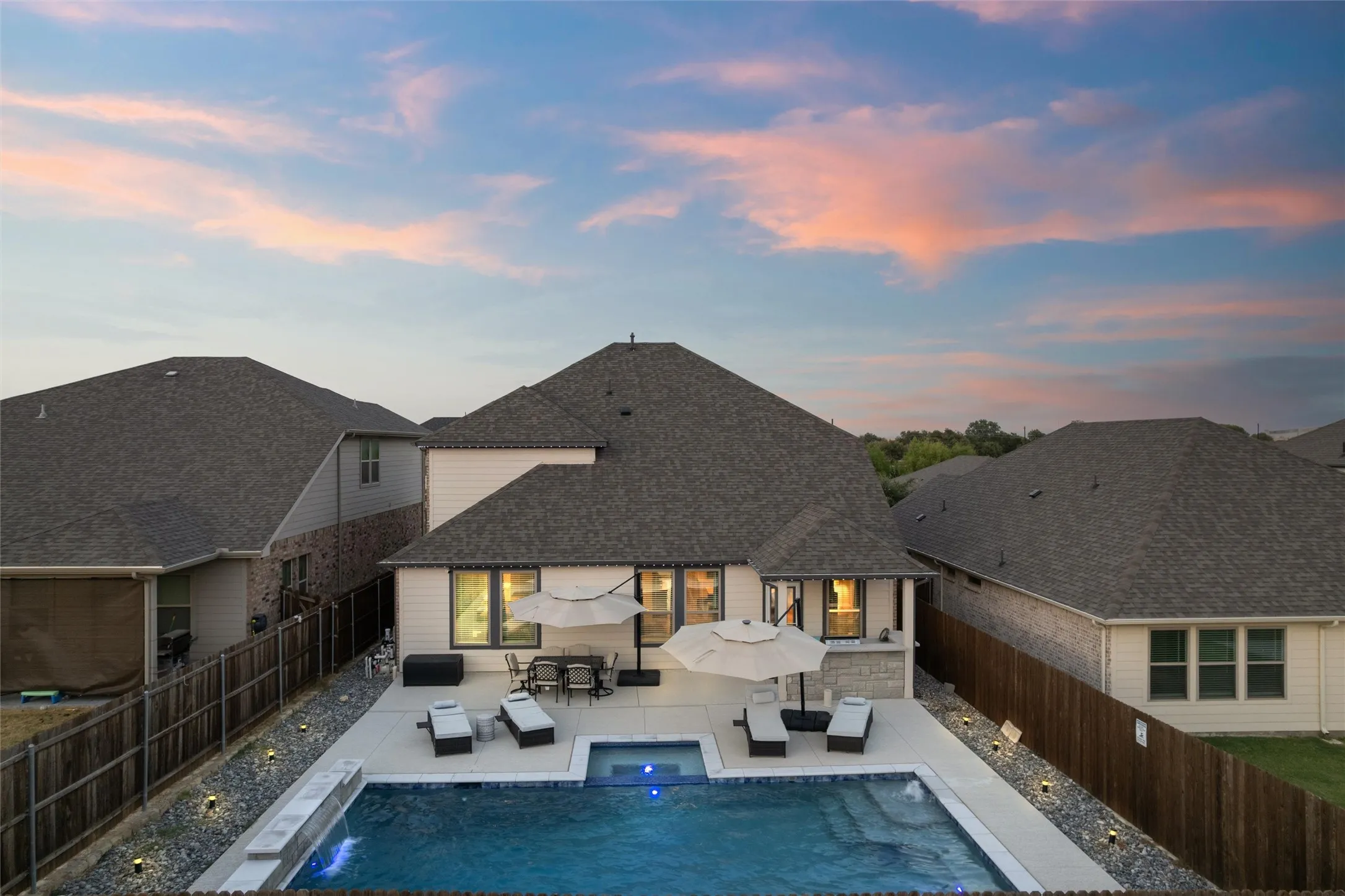 Rear exterior featuring a large swimming pool, integrated spa, and an extended patio