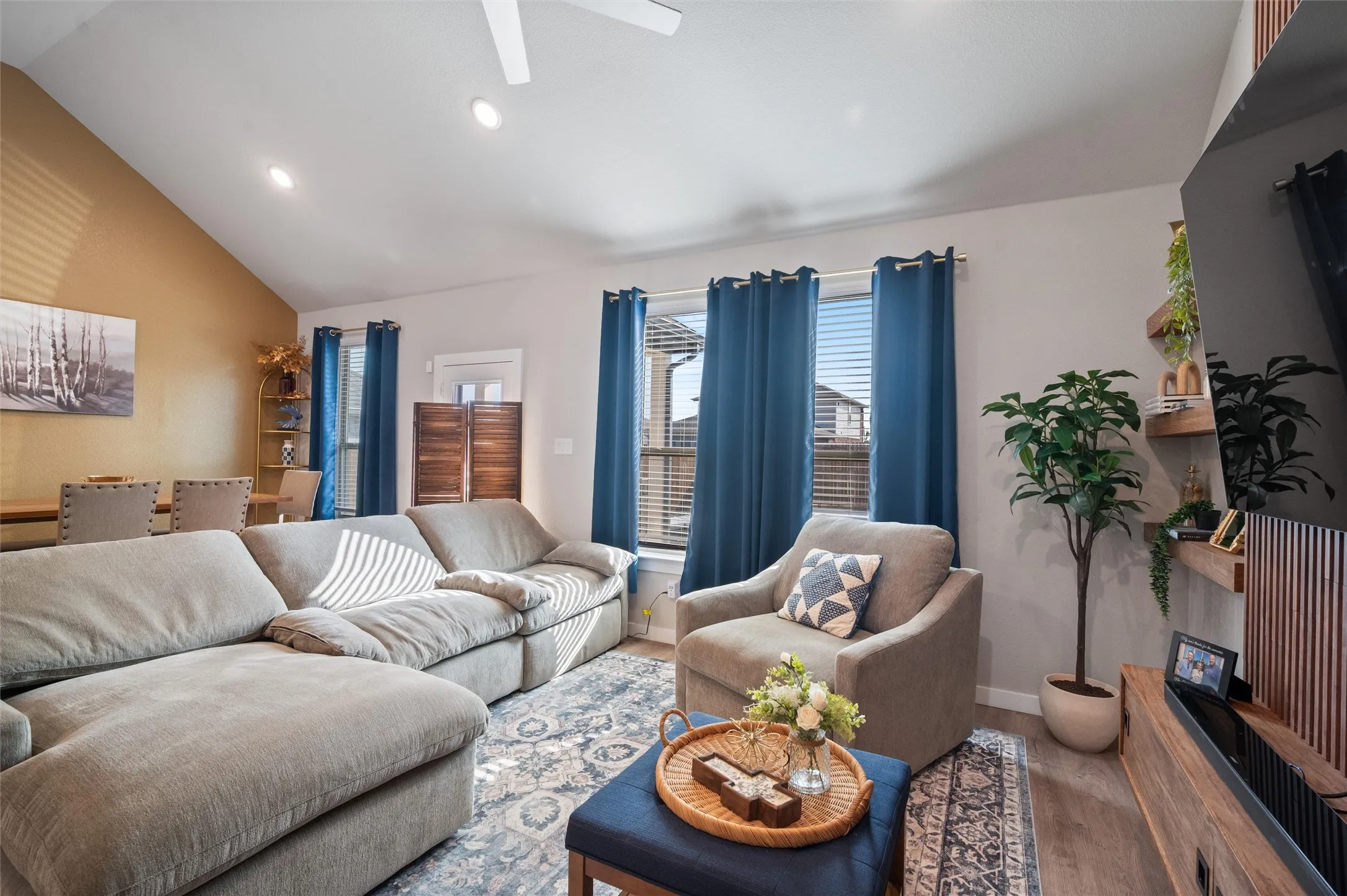 Vaulted ceiling with recessed lighting, wood-finish flooring, multiple windows with blinds, and built-in shelving
