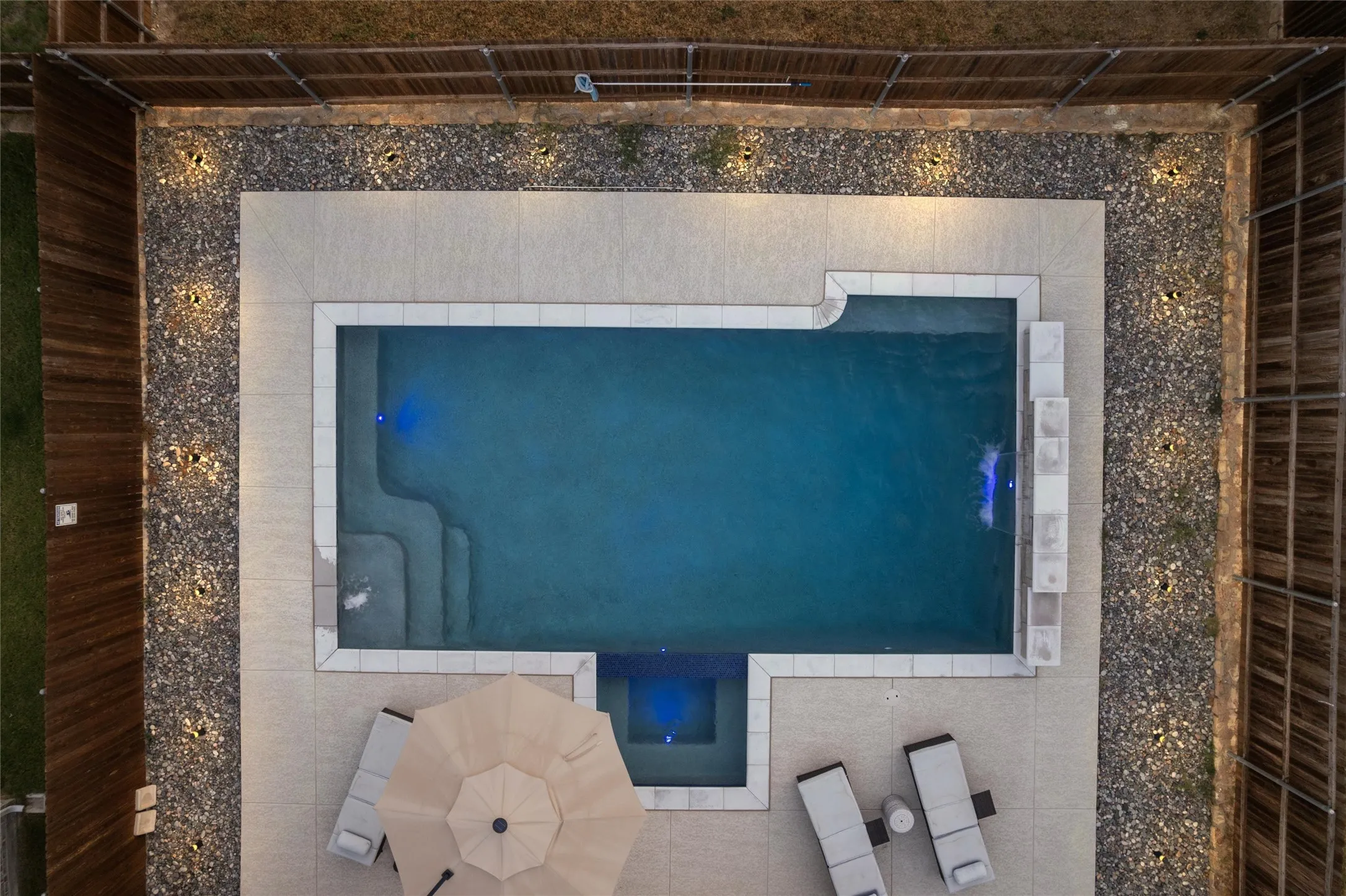 Rectangular swimming pool with integrated spa and steps, surrounded by stone coping and concrete decking