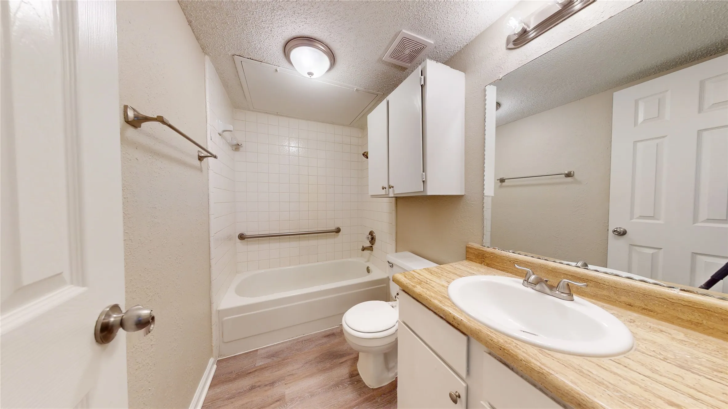 Bathroom featuring a vanity with a laminate countertop, integrated sink, and white cabinetry