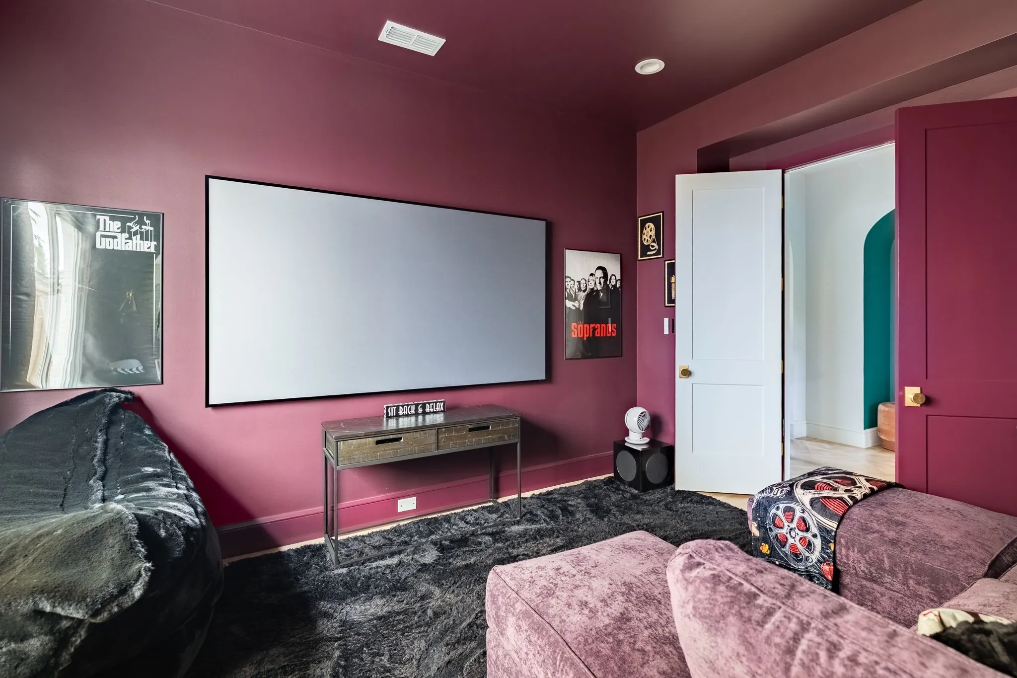 Spacious room featuring a large projection screen, recessed lighting, and a textured area rug