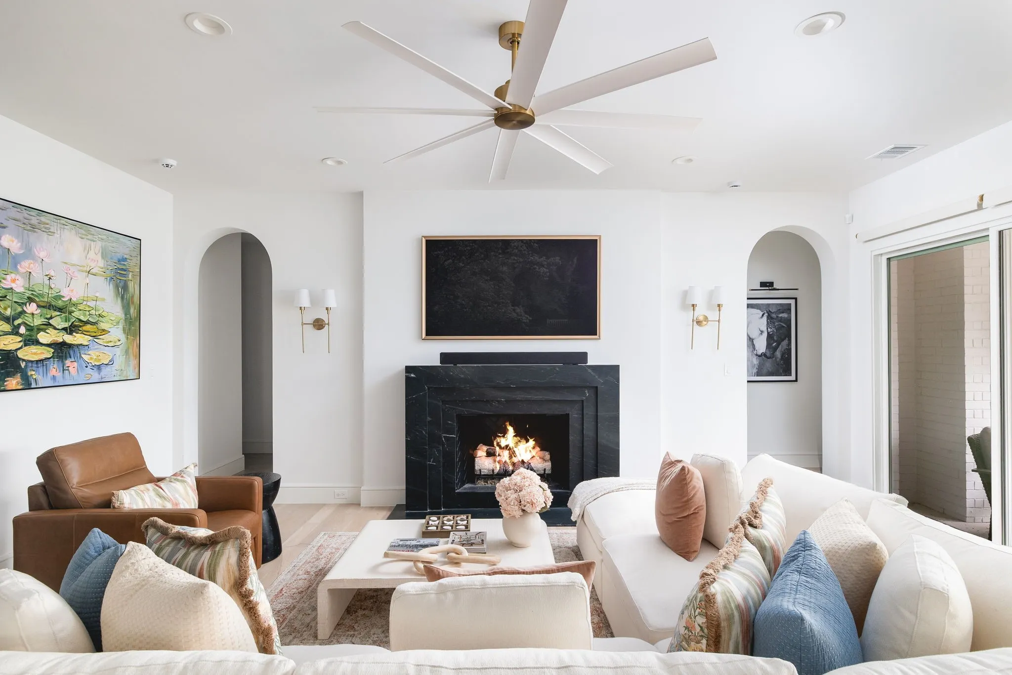 Recessed lighting, arched doorways, a stone fireplace, wood-finish flooring, and sliding glass doors