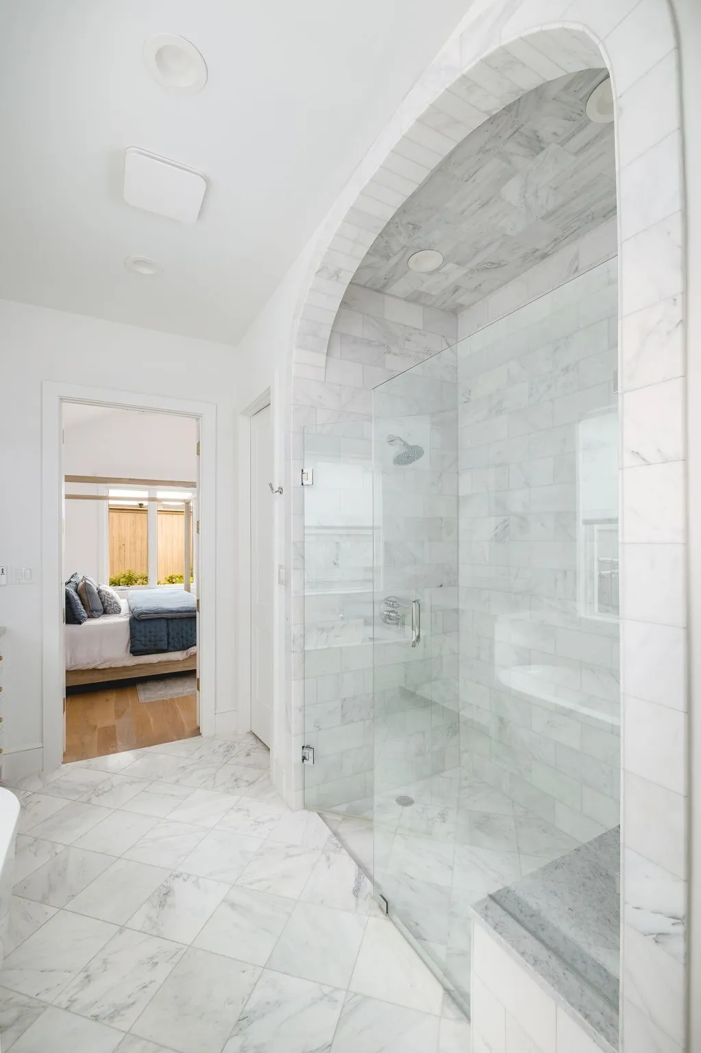 Expansive shower enclosure with glass surround, tiled walls, and built-in bench
