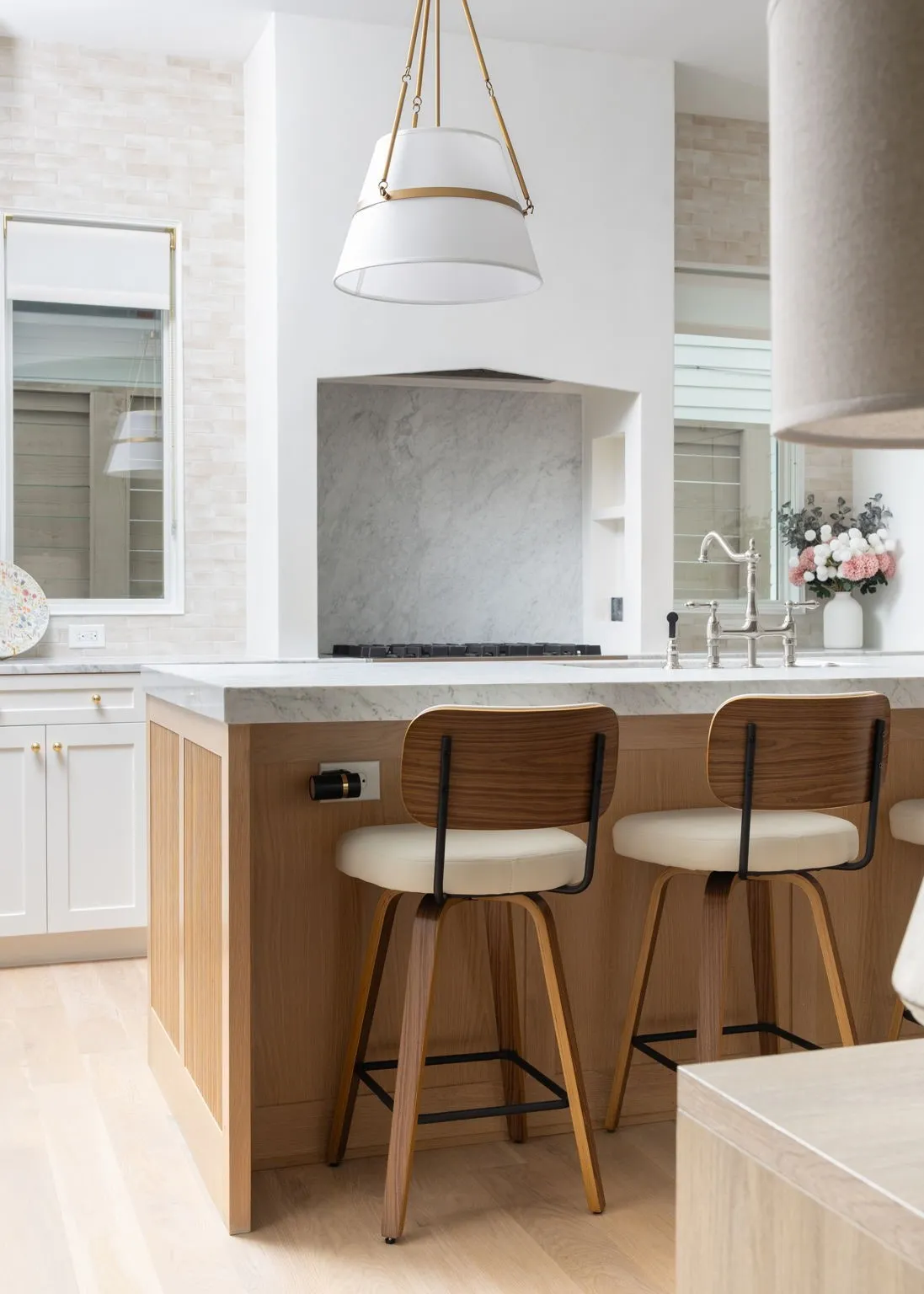 Contemporary kitchen island featuring warm wood cabinetry, a light stone countertop, and seating for two with mid-century modern bar stools