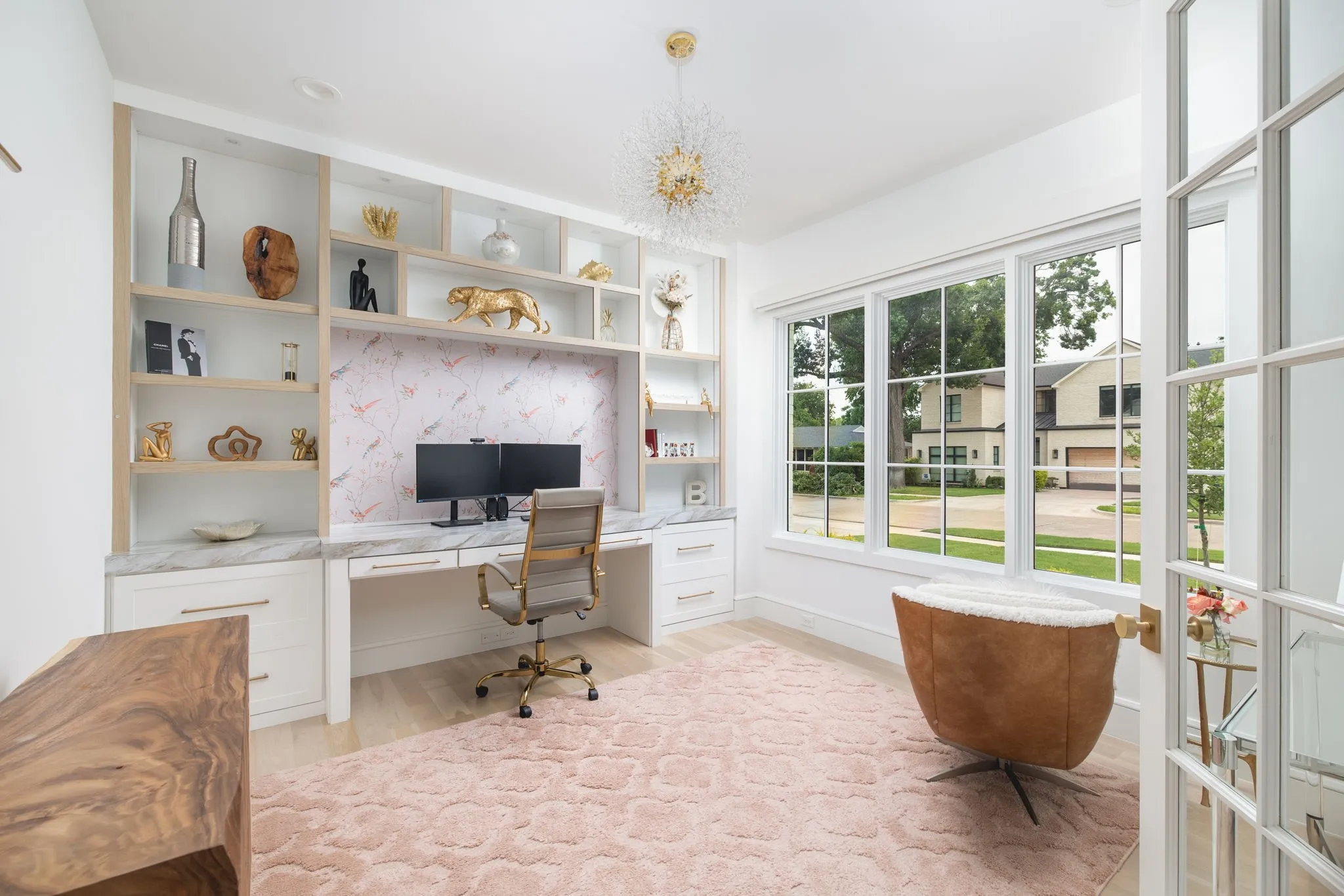 Built-in desk with a marble-finish countertop and integrated shelving, large windows, wood-finish flooring, and French doors