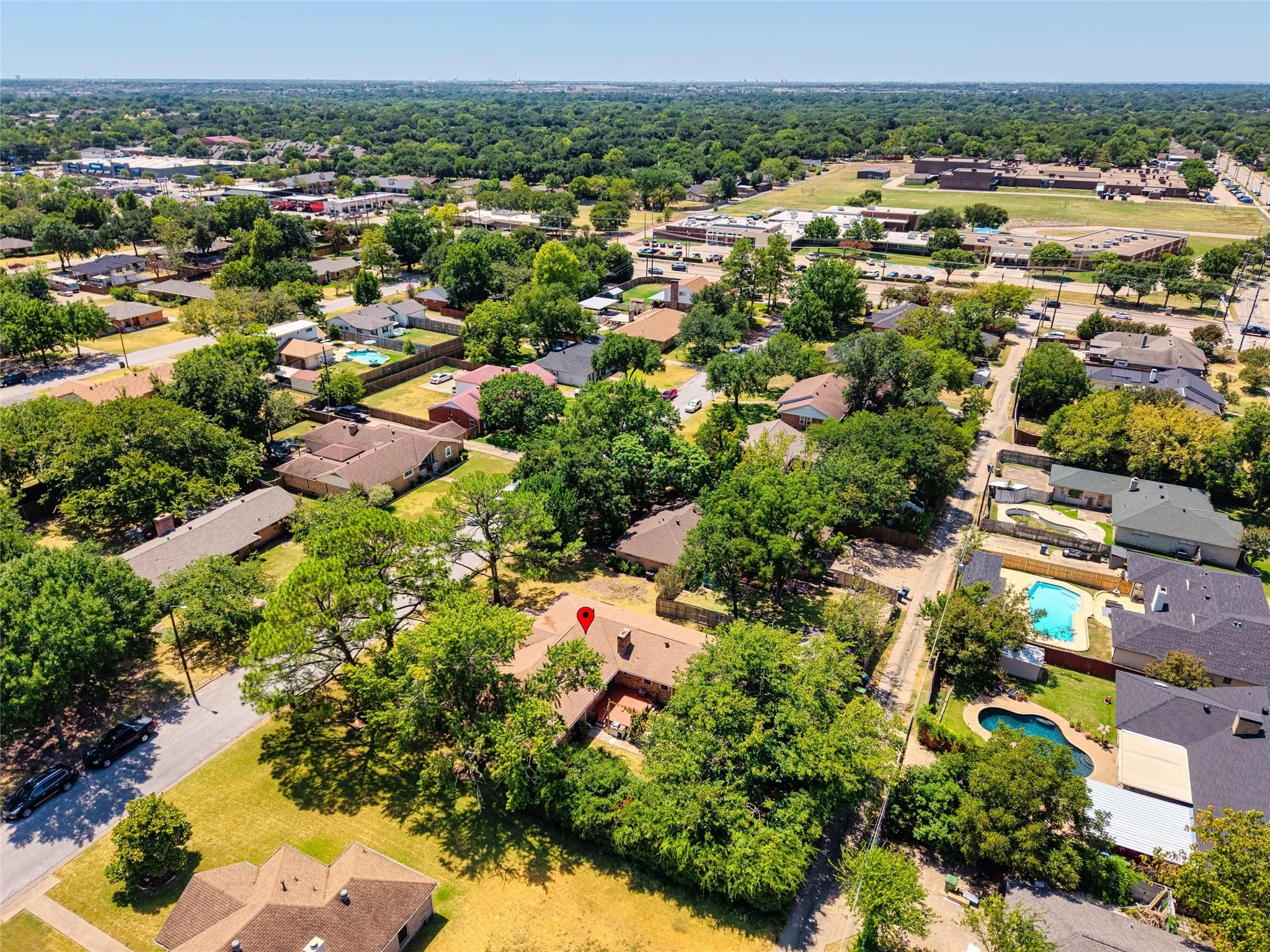 Aerial perspective of the neighborhood featuring lush tree canopy and residential properties