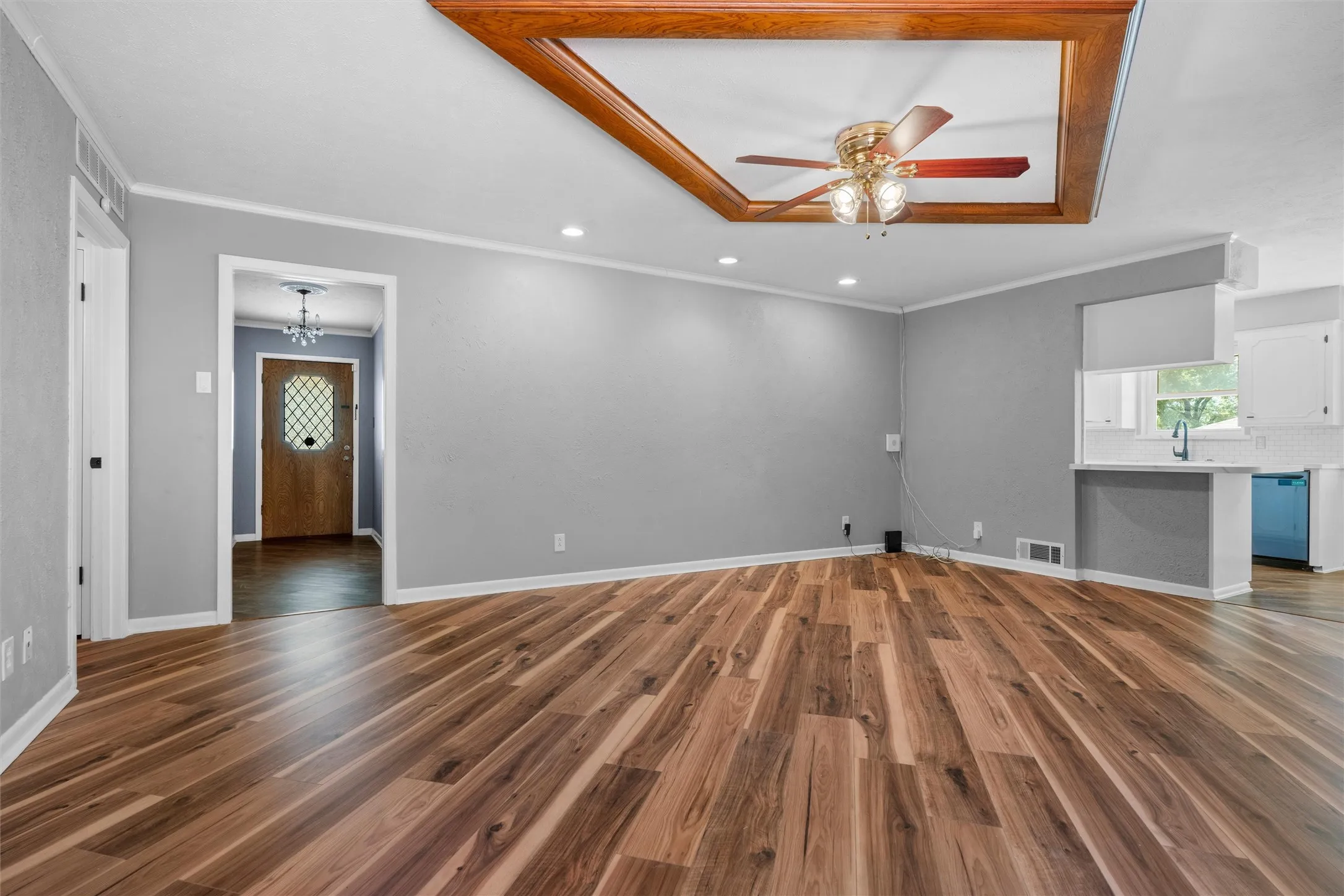 Wood-finish flooring throughout, recessed lighting, and a tray ceiling with a ceiling fan