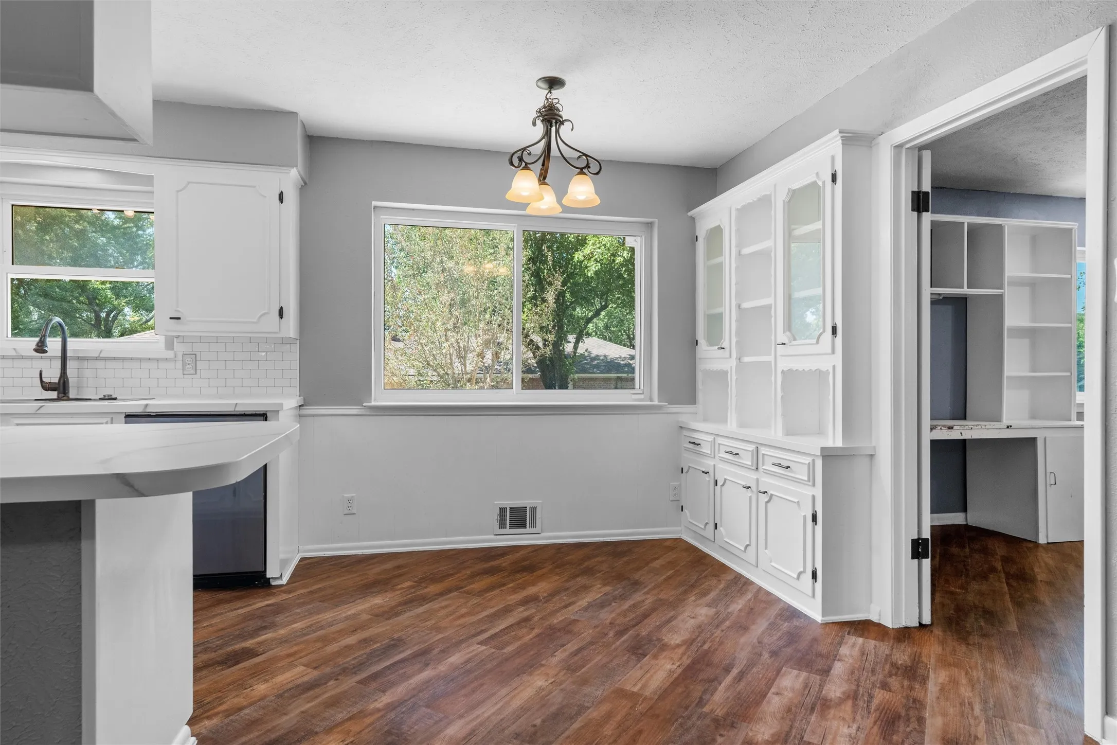 Kitchen featuring white cabinetry, subway tile backsplash, and a breakfast bar with stone-finish countertop