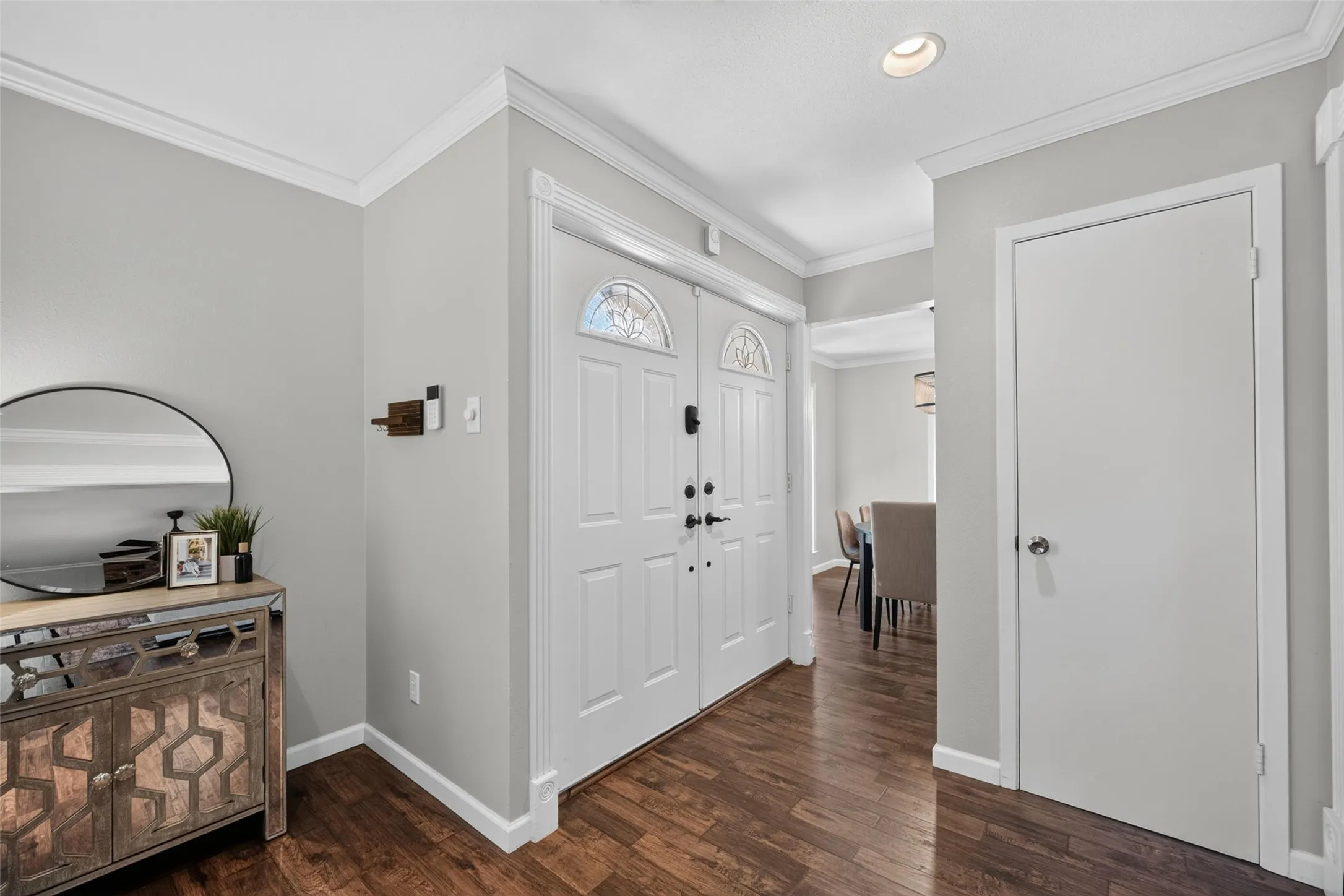 Double entry doors with leaded glass accents, rich wood-finish flooring, recessed ceiling lighting, and crown molding