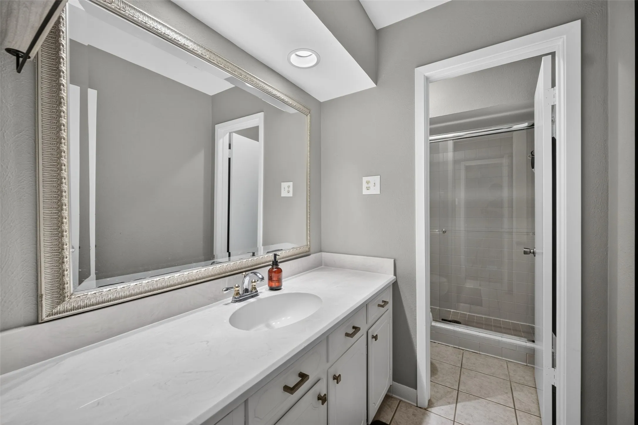 Vanity with a large framed mirror, recessed lighting, and a white countertop