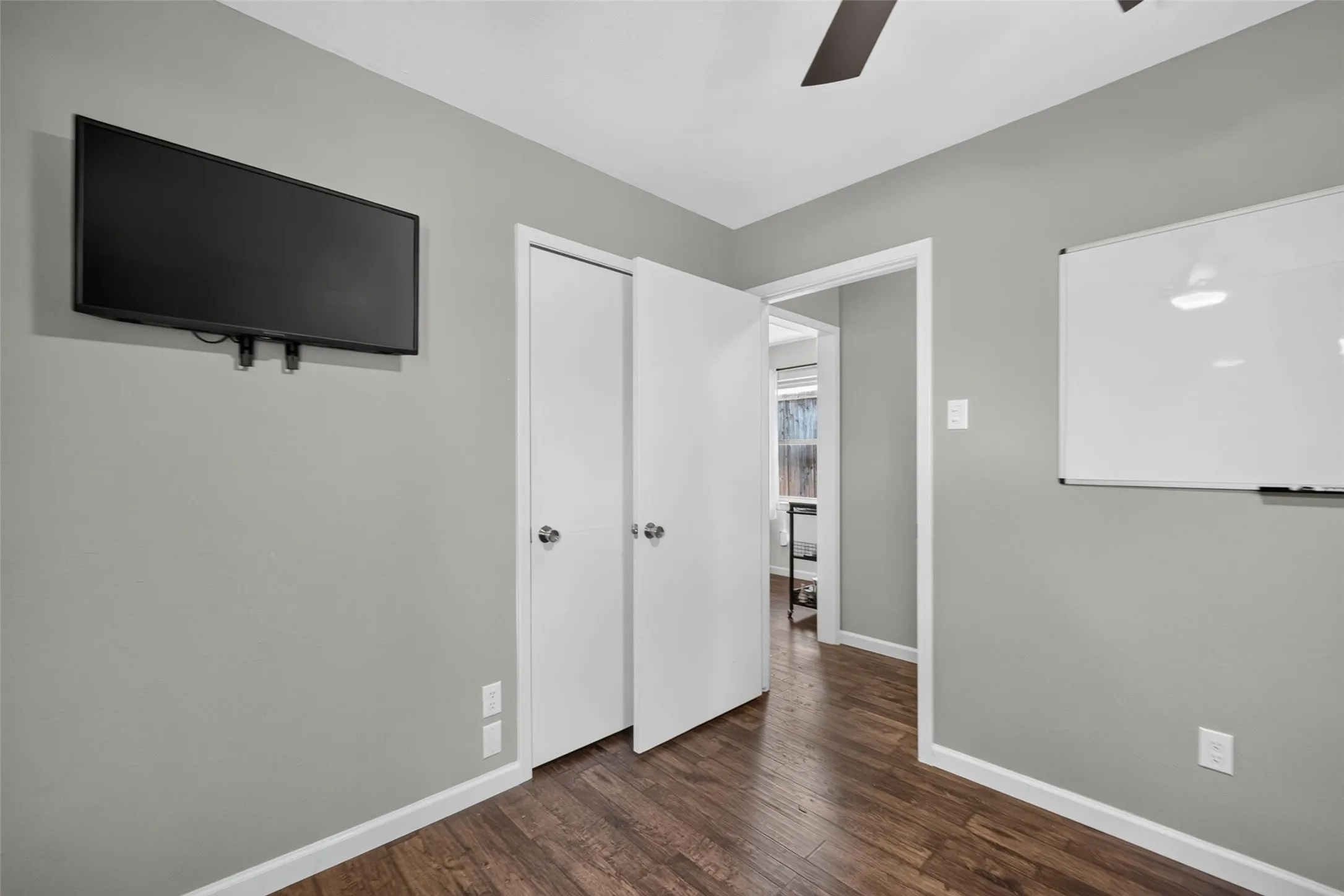 Wood-finish flooring, light grey wall paint, and a ceiling fan