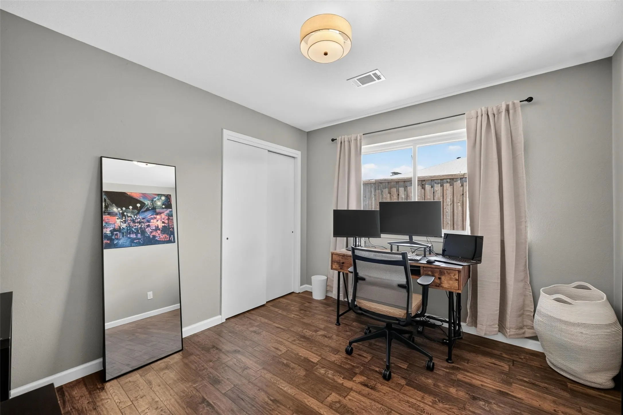Spacious room featuring wood-finish flooring, a double-pane window, and a built-in closet with sliding doors