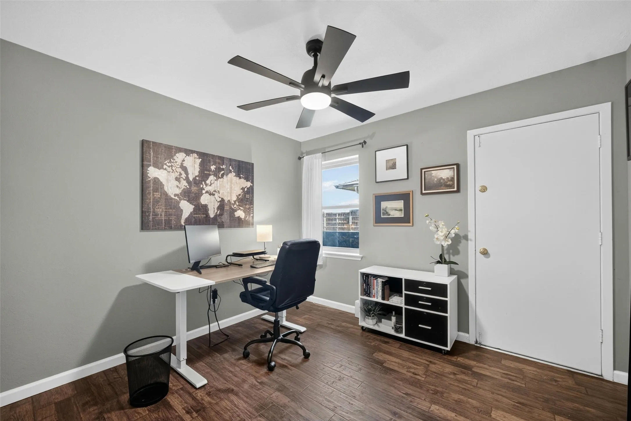 Wood-finish flooring, ceiling fan with integrated lighting, neutral wall palette, and white trim