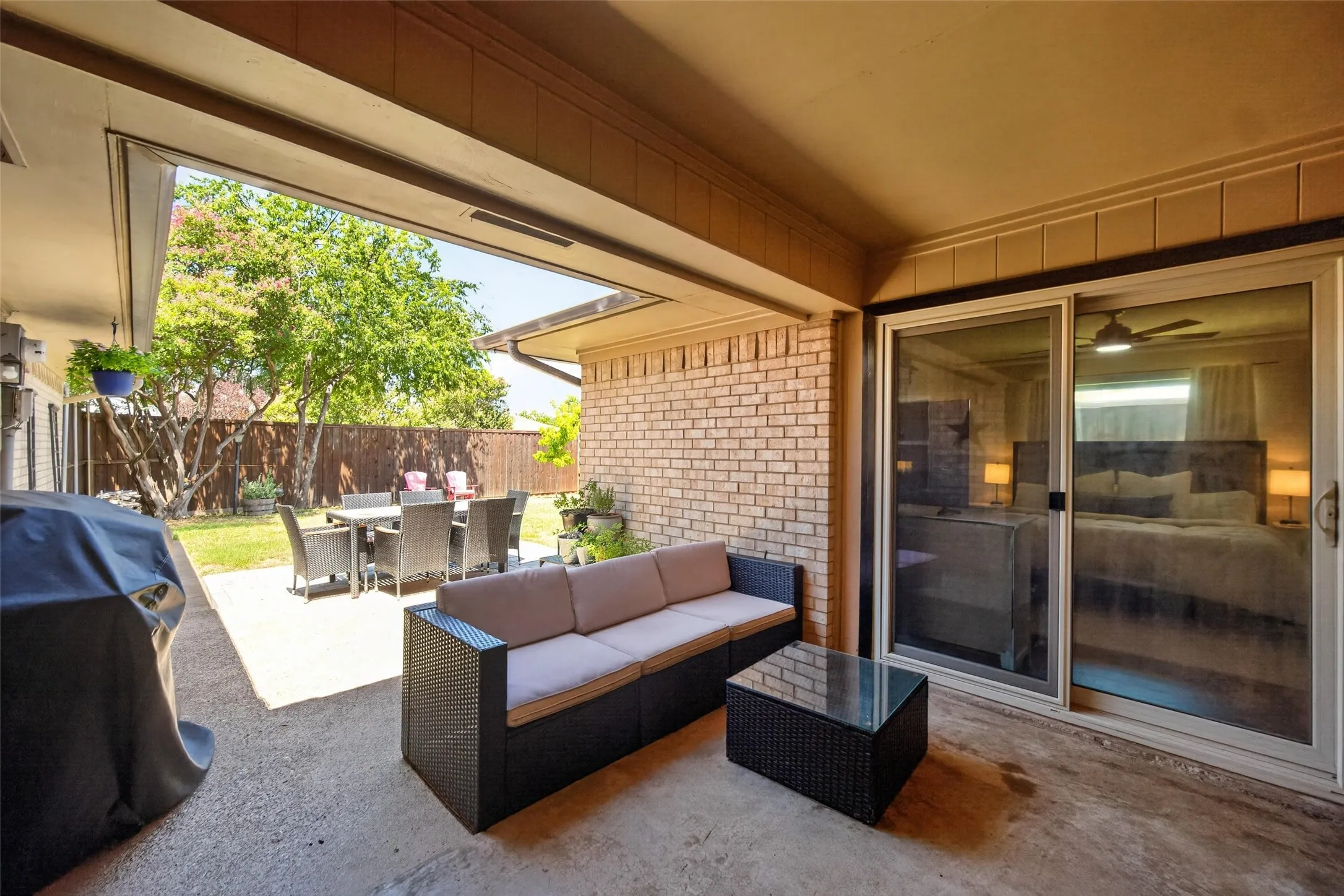 Covered patio with concrete flooring, brick exterior wall, and sliding glass door access to an interior room