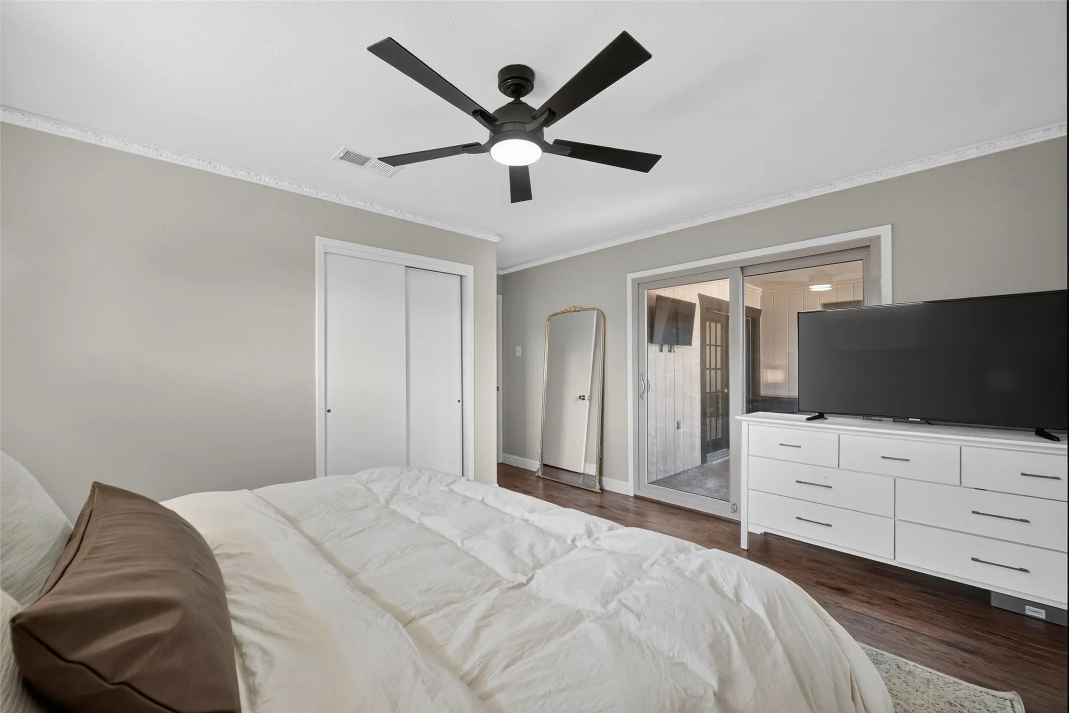 Wood-finish flooring, sliding glass door, modern ceiling fan, and white sliding closet doors