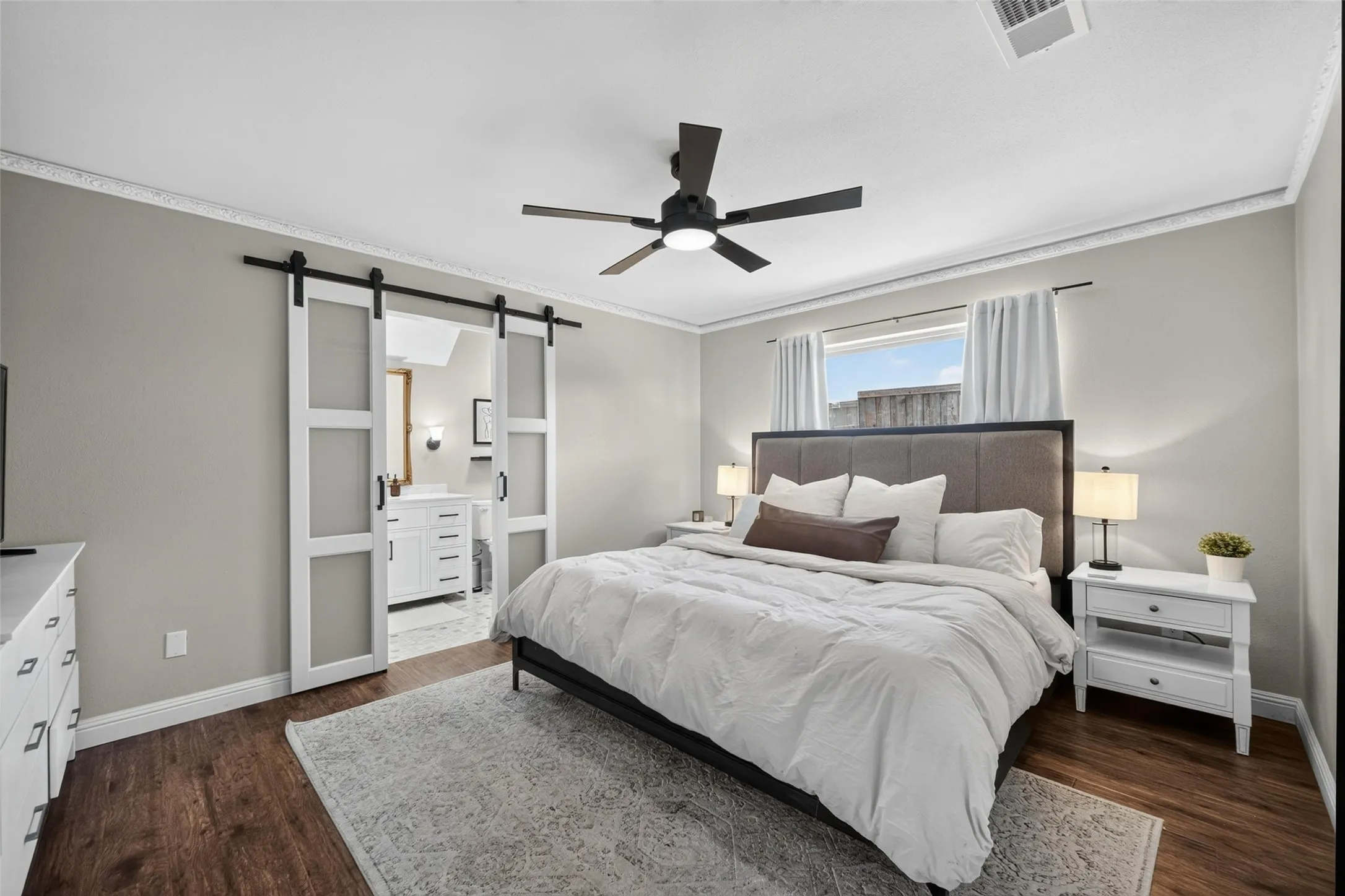 Wood-finish flooring, ceiling fan with integrated lighting, and frosted panel barn doors
