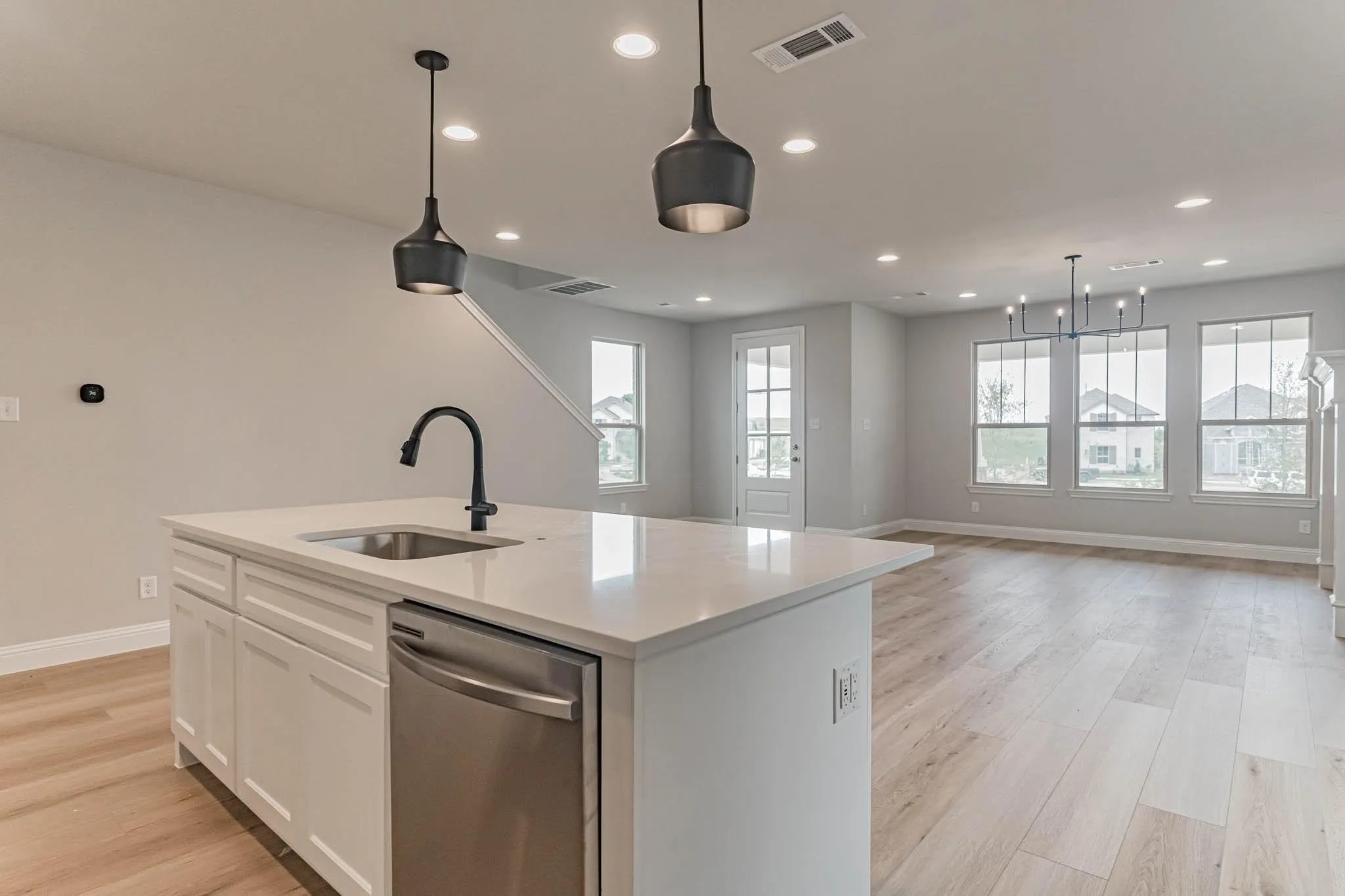 Kitchen island featuring a stainless steel sink with a matte black faucet, white cabinetry, and a stainless steel dishwasher