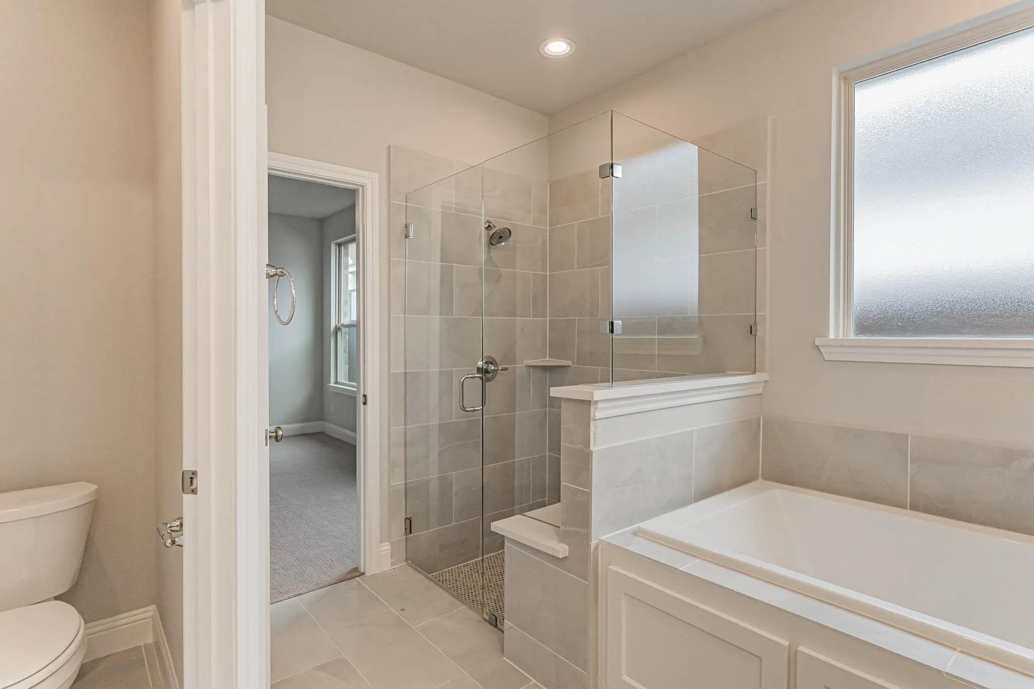 Glass-enclosed shower with tile surround and integrated bench