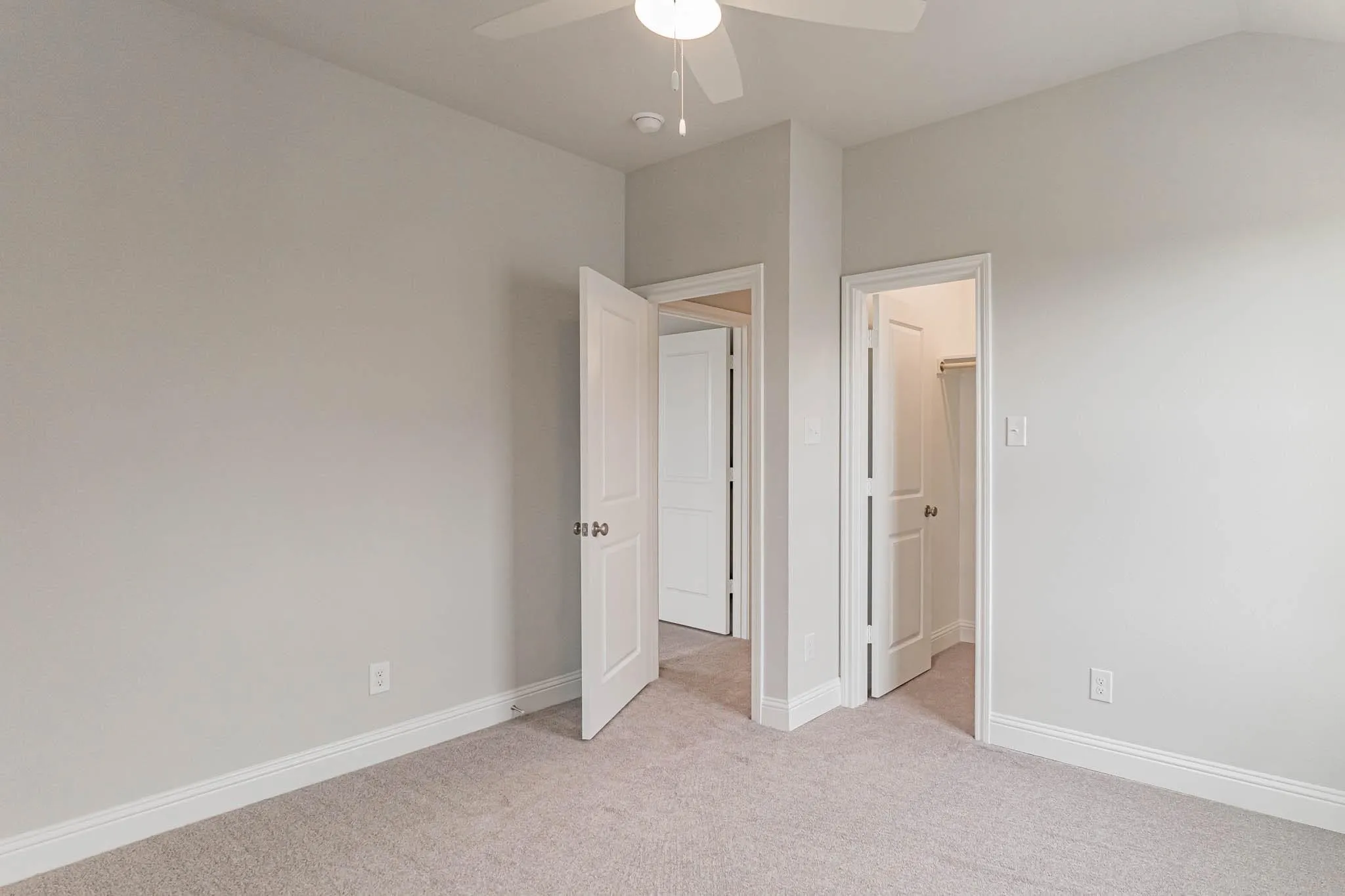 Neutral wall paint with white trim, light-colored carpet flooring, and a ceiling fan with integrated lighting