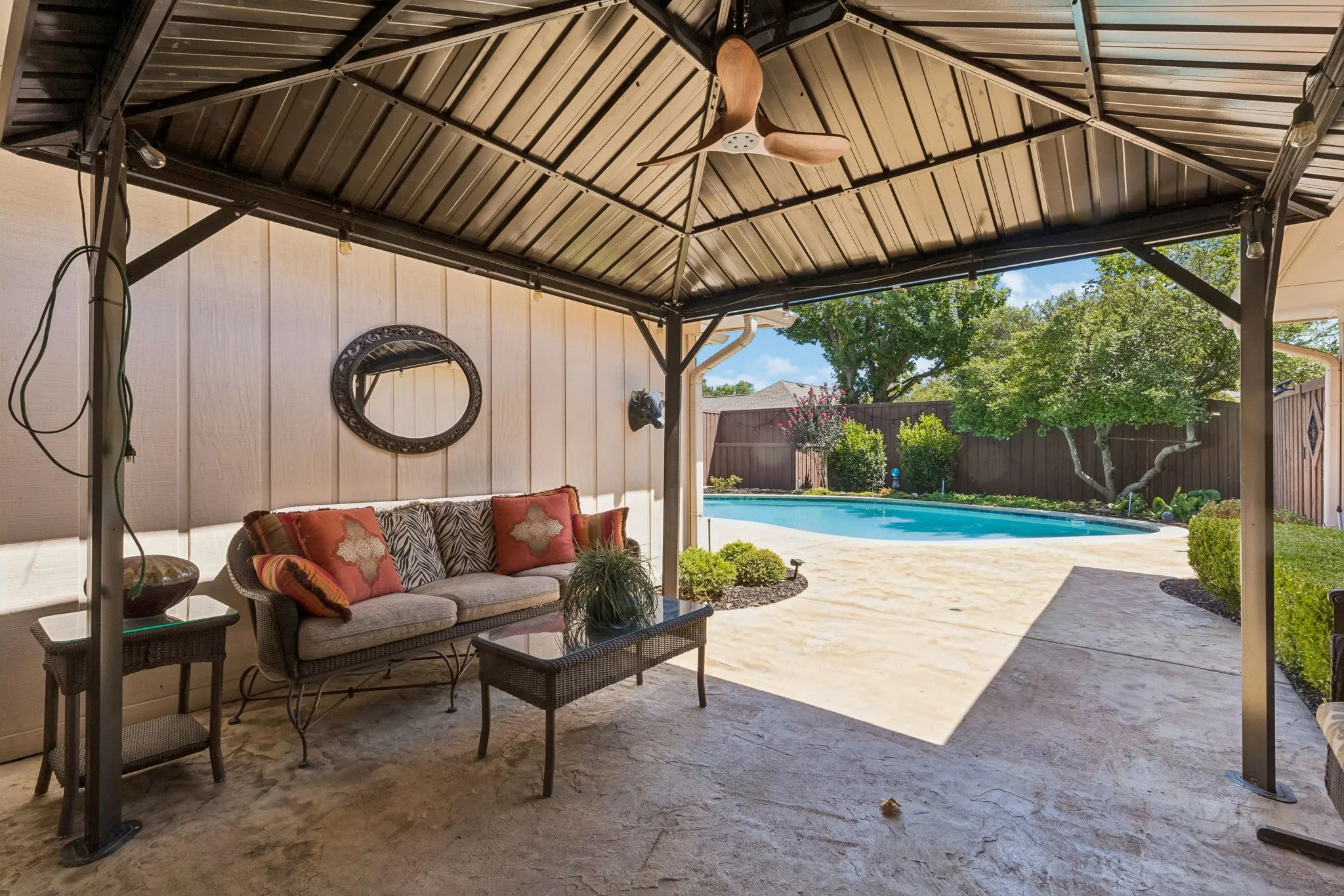 Spacious covered patio with a ceiling fan opening to the pool