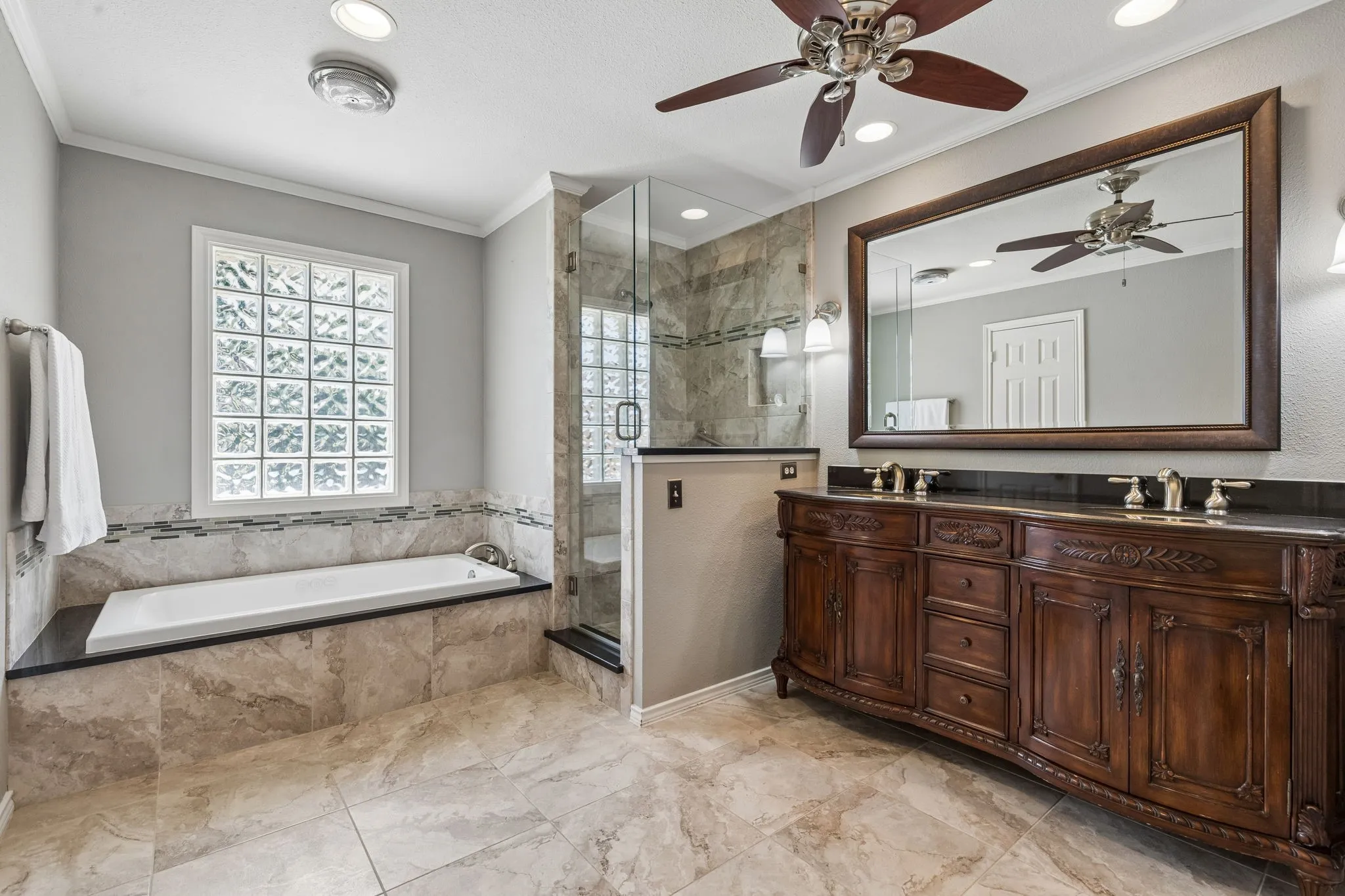 Primary bath updated with tiled flooring frameless glass shower enclosure and a vanity with dual sinks