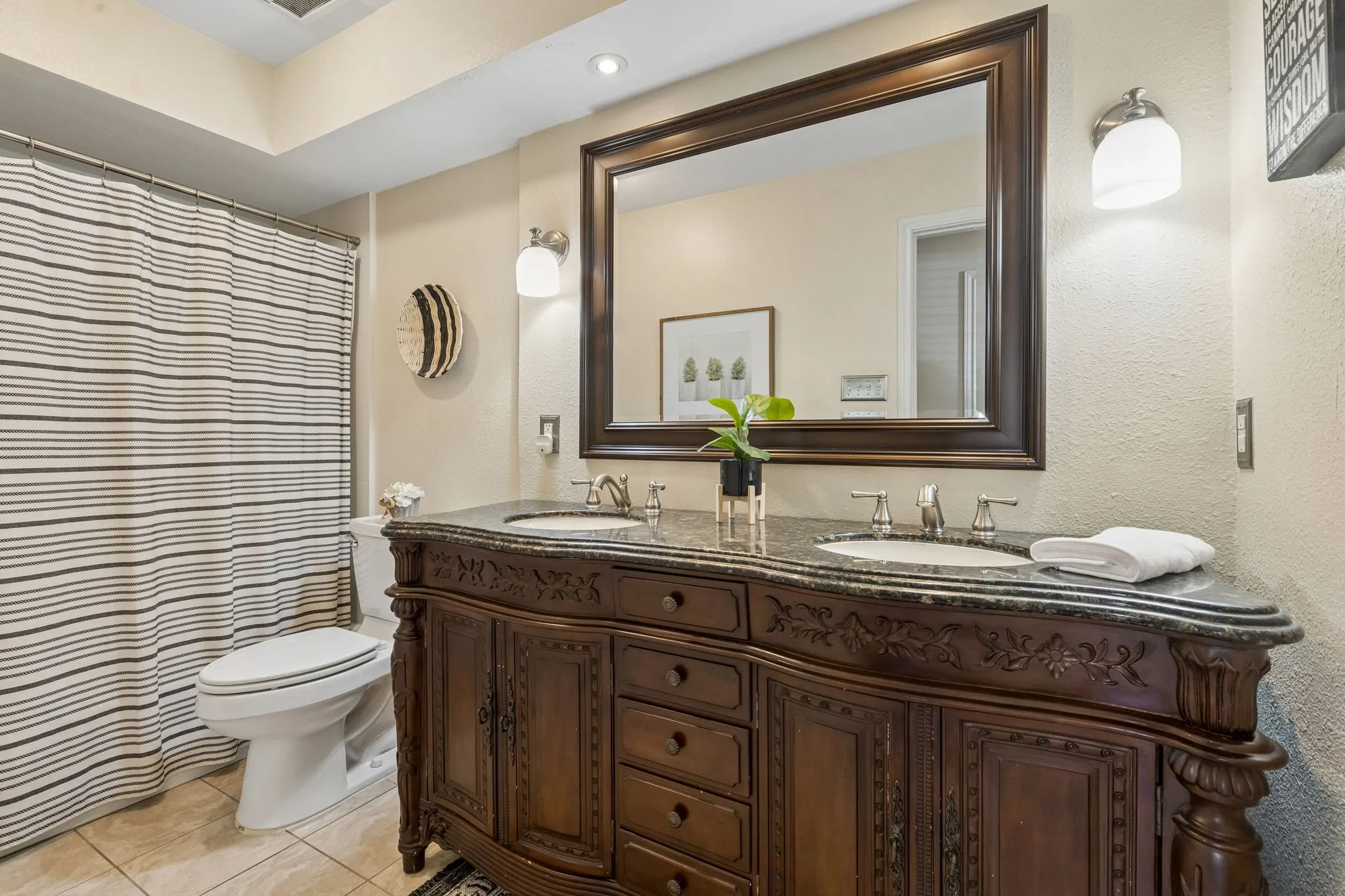 Double vanity with decorative wood cabinetry, integrated sinks, and stone countertop