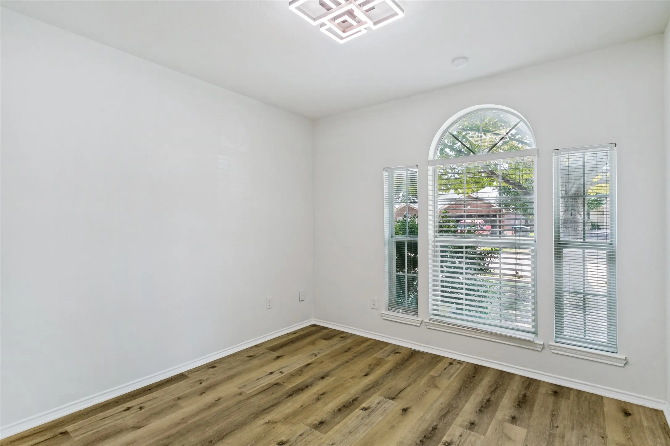 Wood-finish flooring, white walls, and a modern ceiling light fixture
