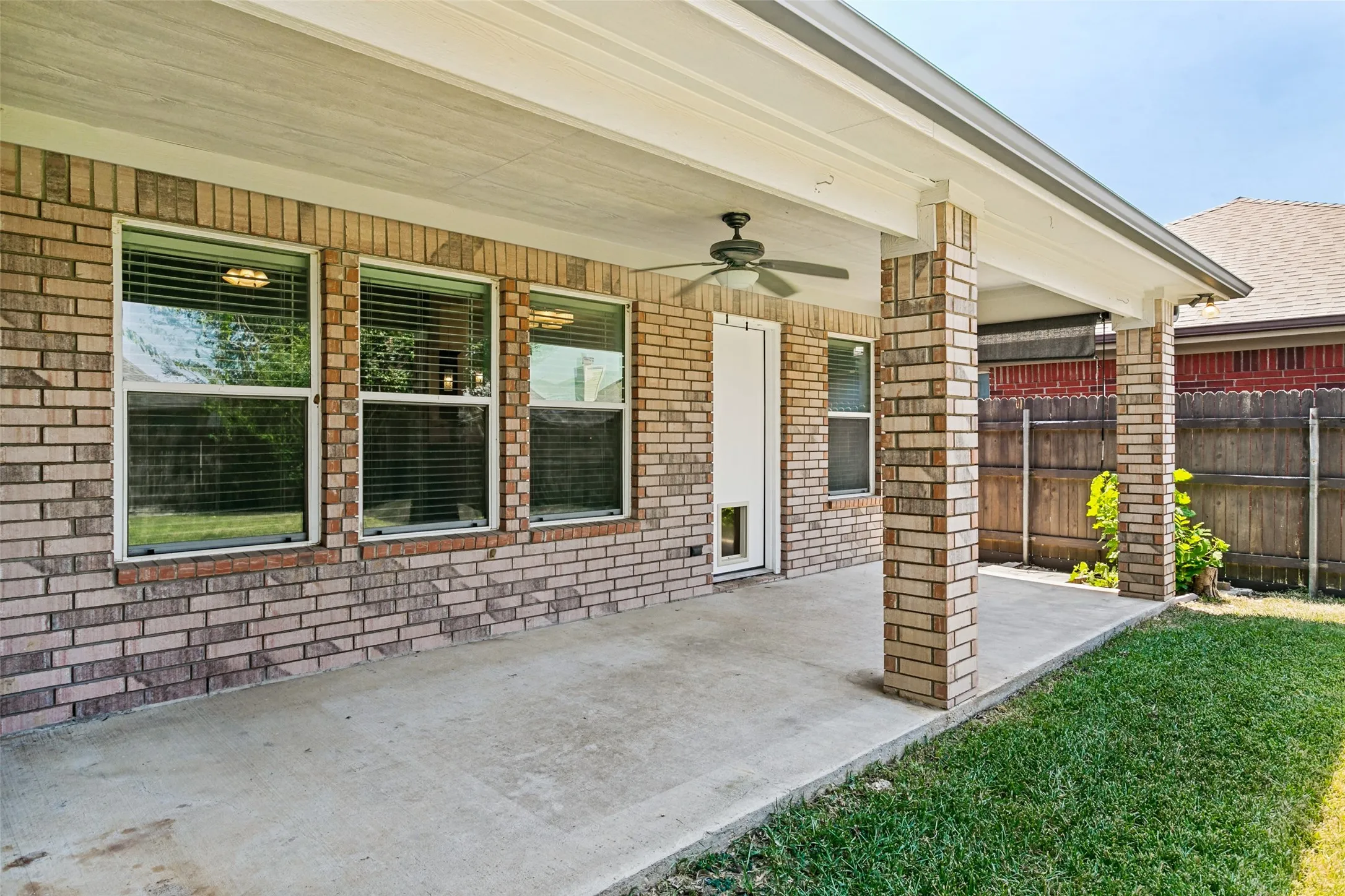 Covered patio with brick columns, a ceiling fan, and concrete flooring