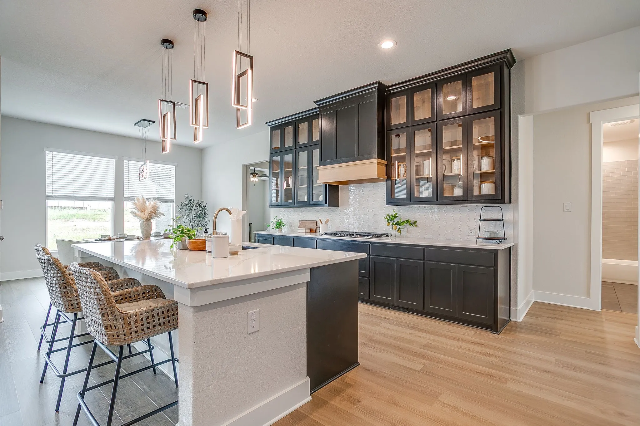 Open-concept kitchen featuring an island with counter seating, dark cabinetry, light-toned countertops, and wood-finish flooring