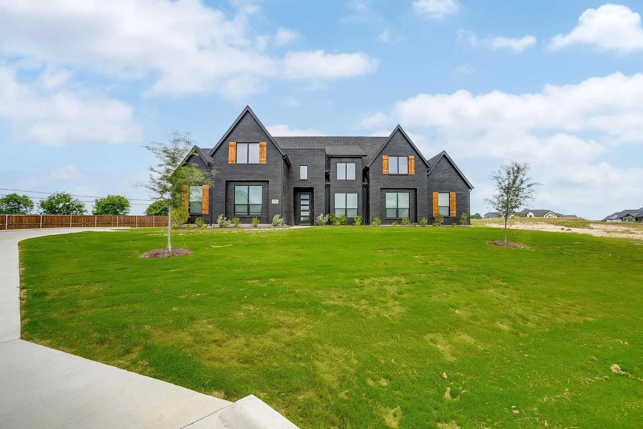 Two-story exterior with dark brick siding, peaked gables, and wood-toned window shutters
