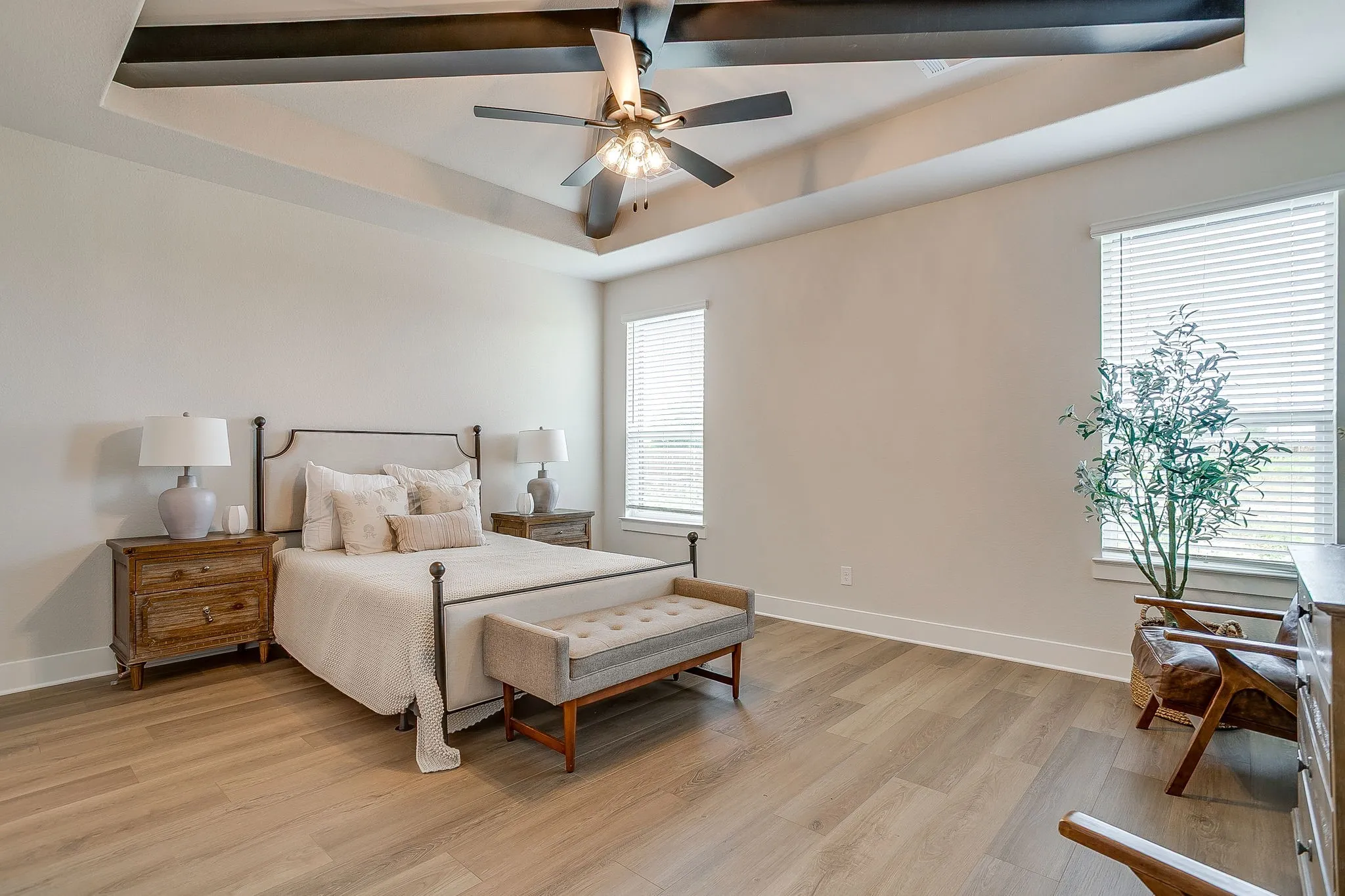 Tray ceiling with exposed wood-look beams and ceiling fan