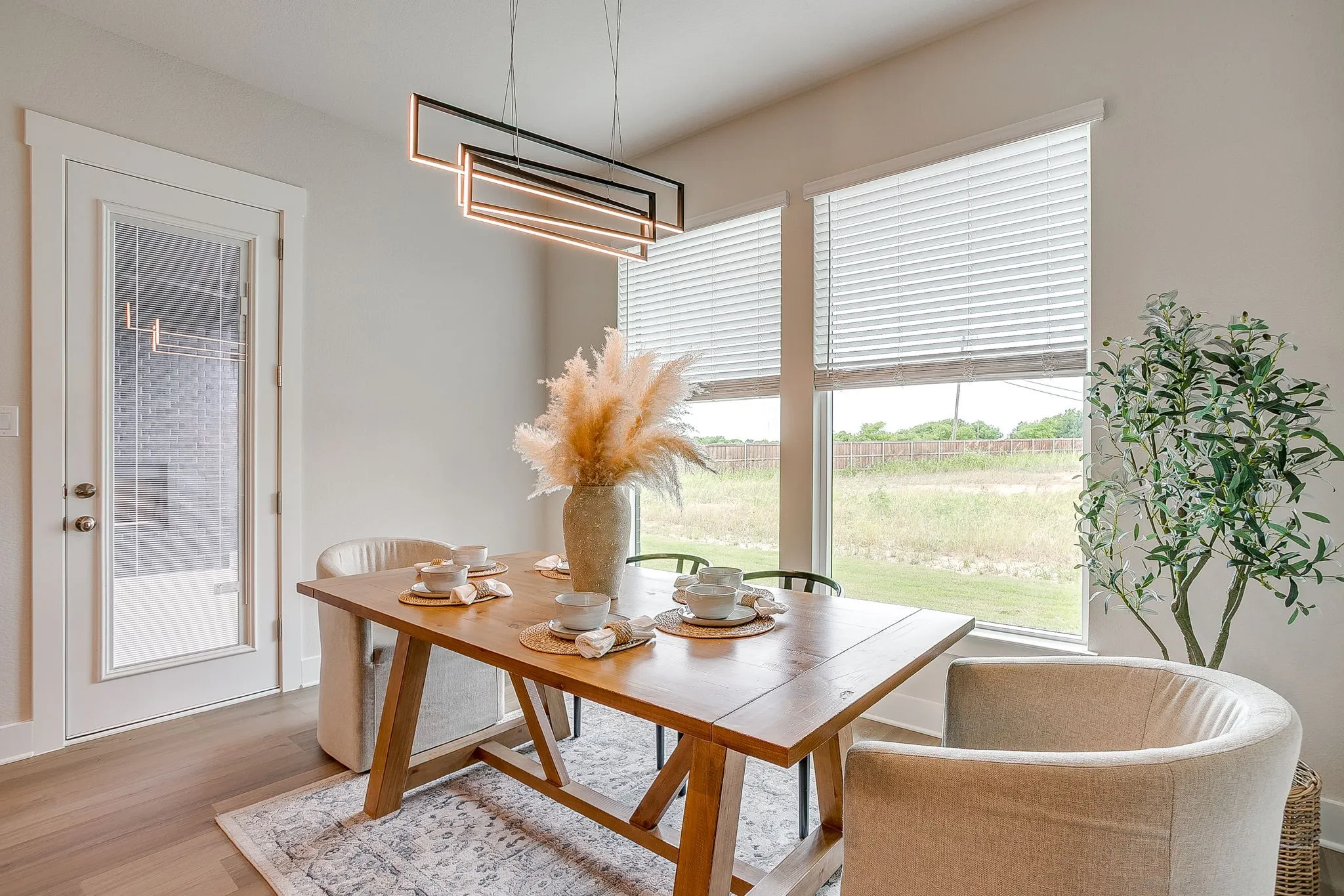 Dining area with wood-finish flooring, a modern linear chandelier, and expansive windows