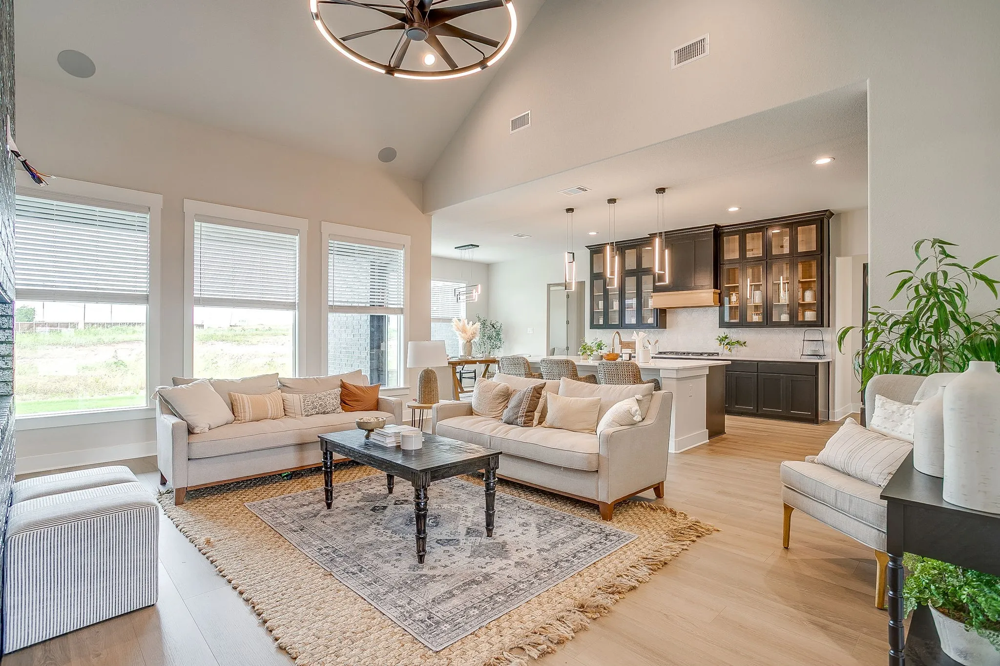 Vaulted ceiling with a contemporary light fixture, wood-finish flooring, and multiple windows