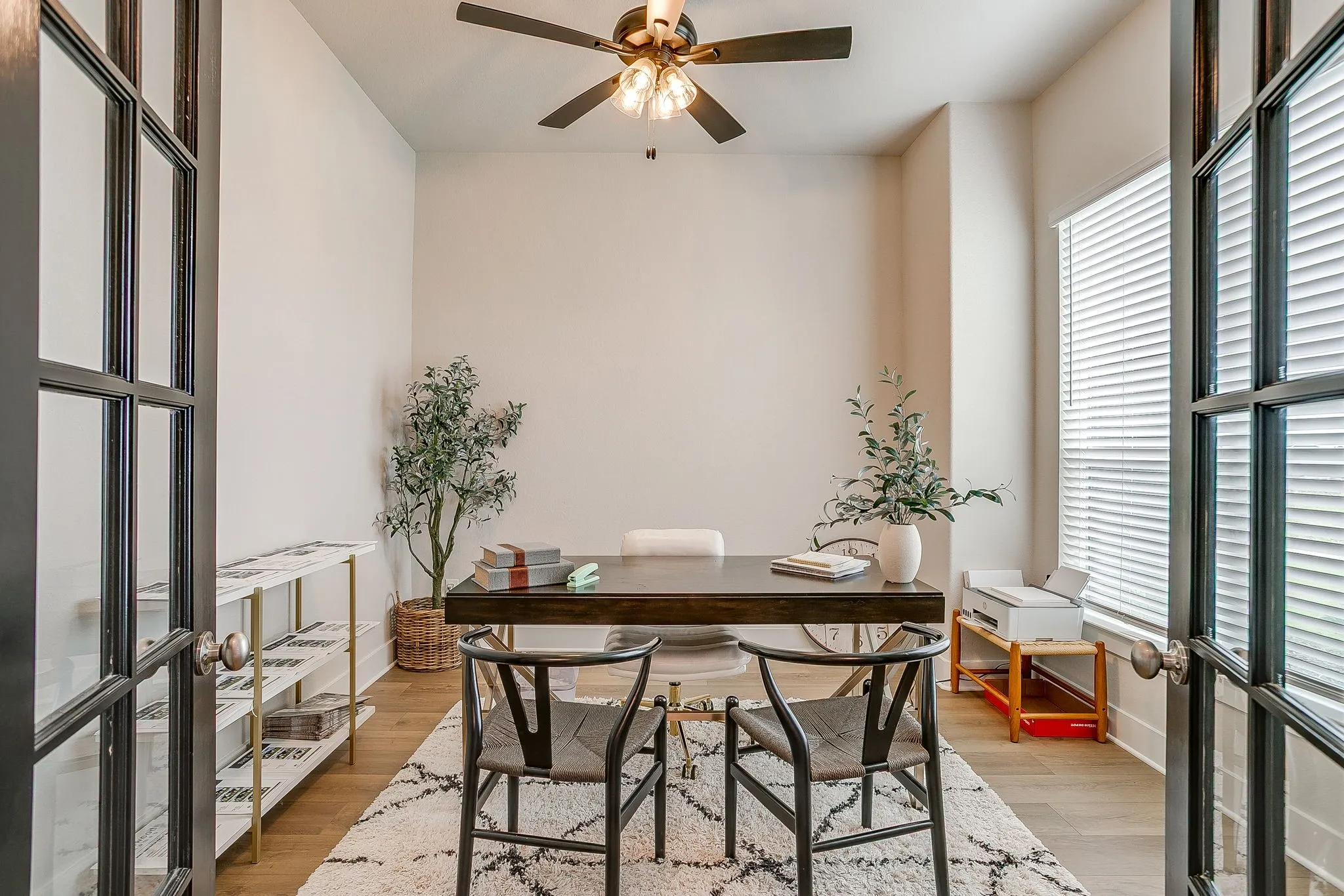 Double doors with gridded glass panels, wood-finish flooring, and a ceiling fan with integrated lighting