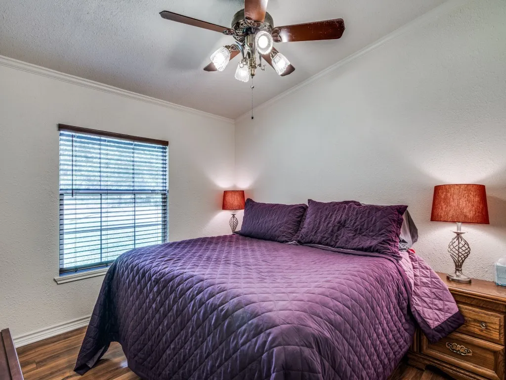 Wood-finish flooring with a window featuring blinds