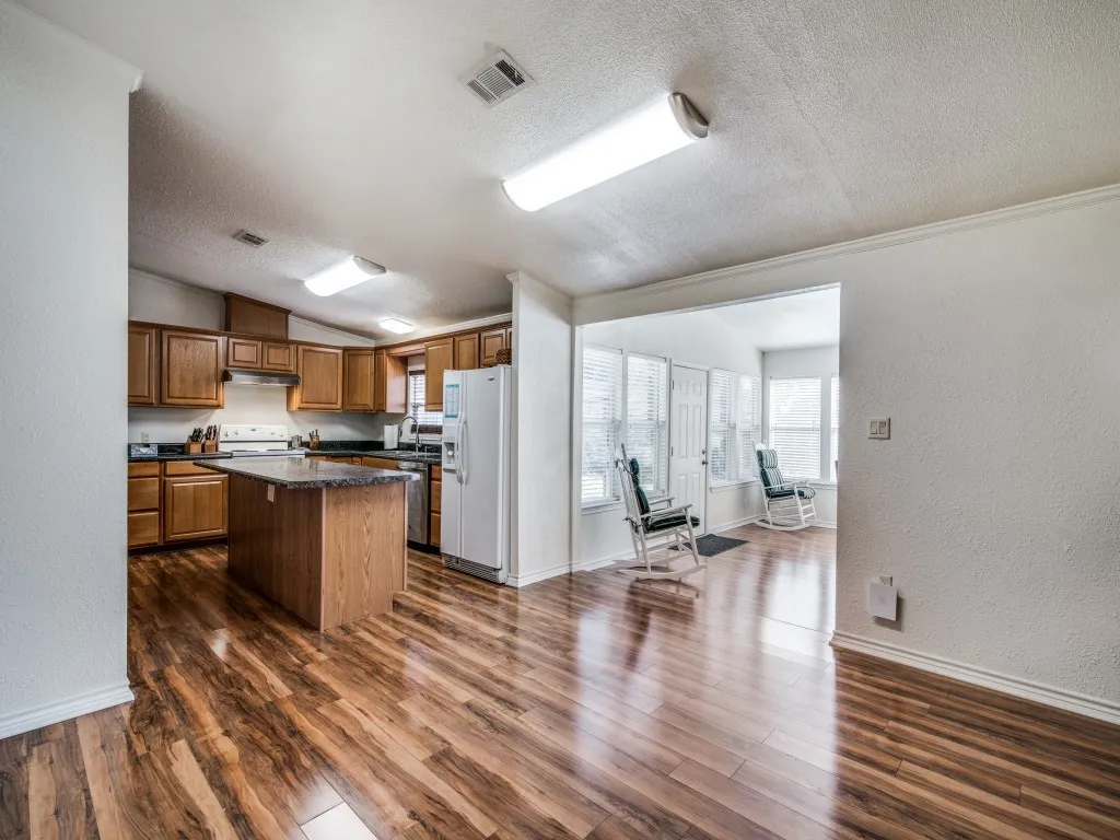 Kitchen with wood-finish flooring, wood cabinetry, stone countertops, and a central island