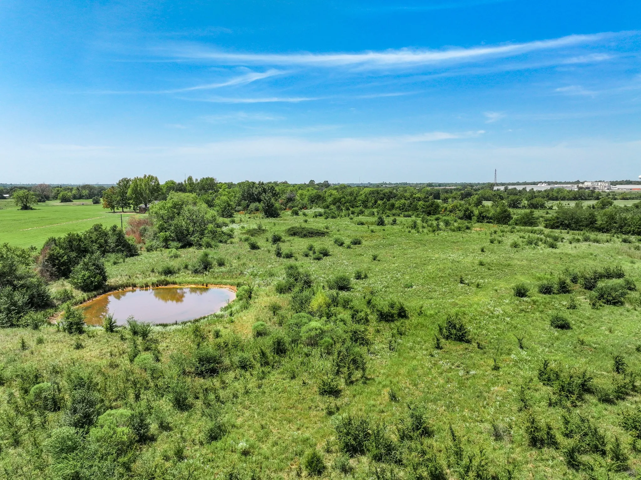 Expansive green landscape featuring a natural pond and varied foliage