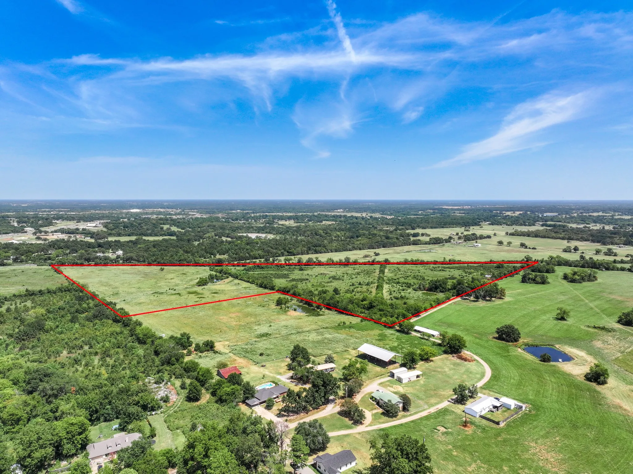 Expansive rural land parcel featuring varied terrain, a clear pond, and established tree lines