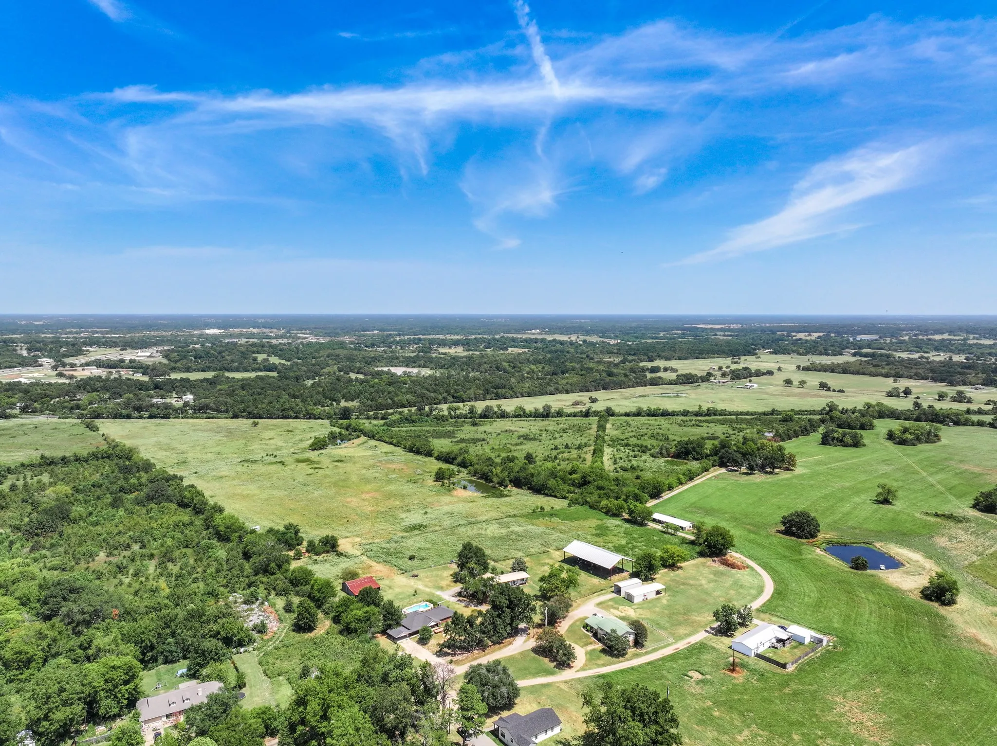 Expansive agricultural land featuring a natural pond, multiple structures, and a clear perimeter