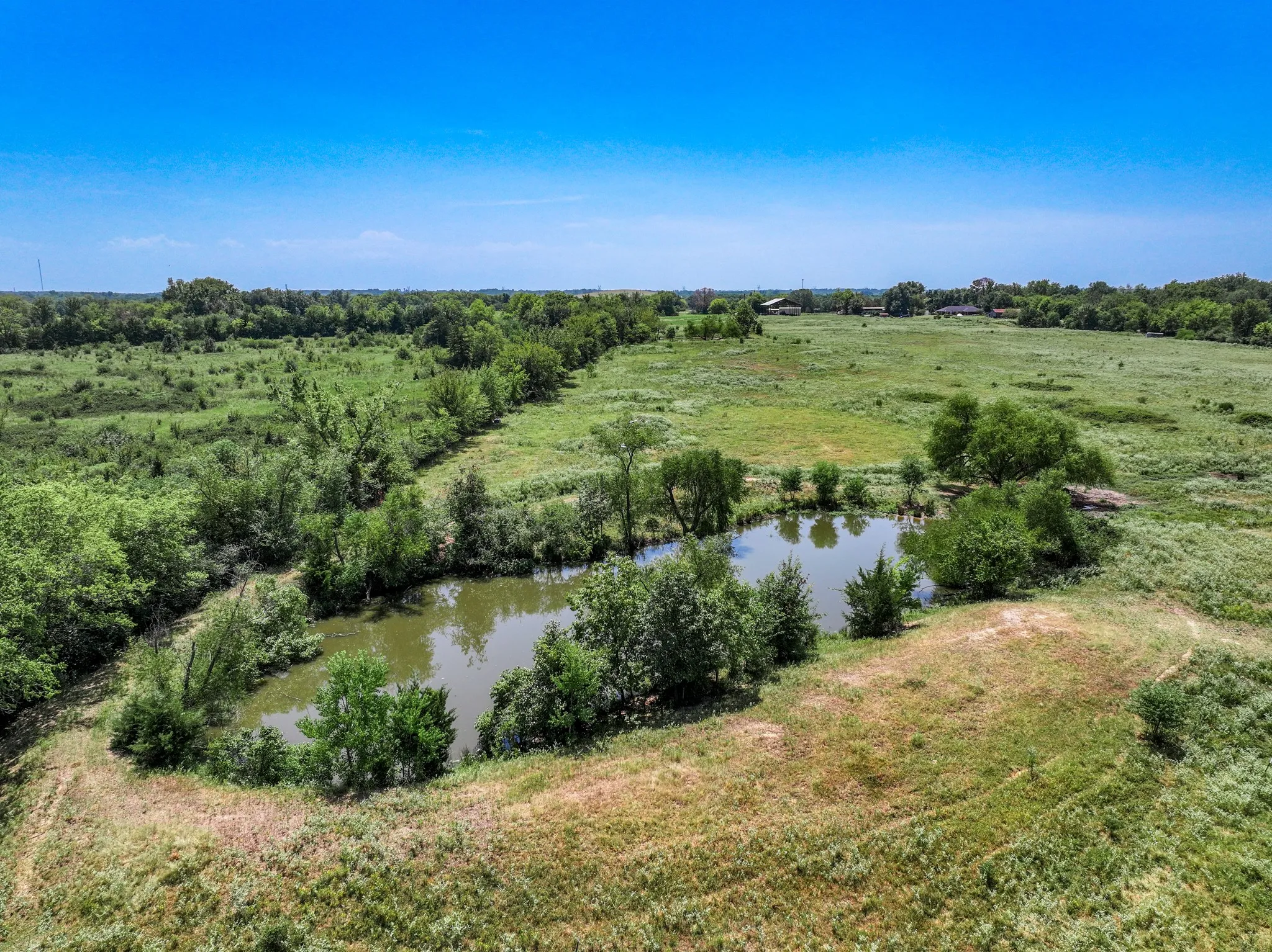 Expansive green fields featuring a natural pond and abundant mature trees