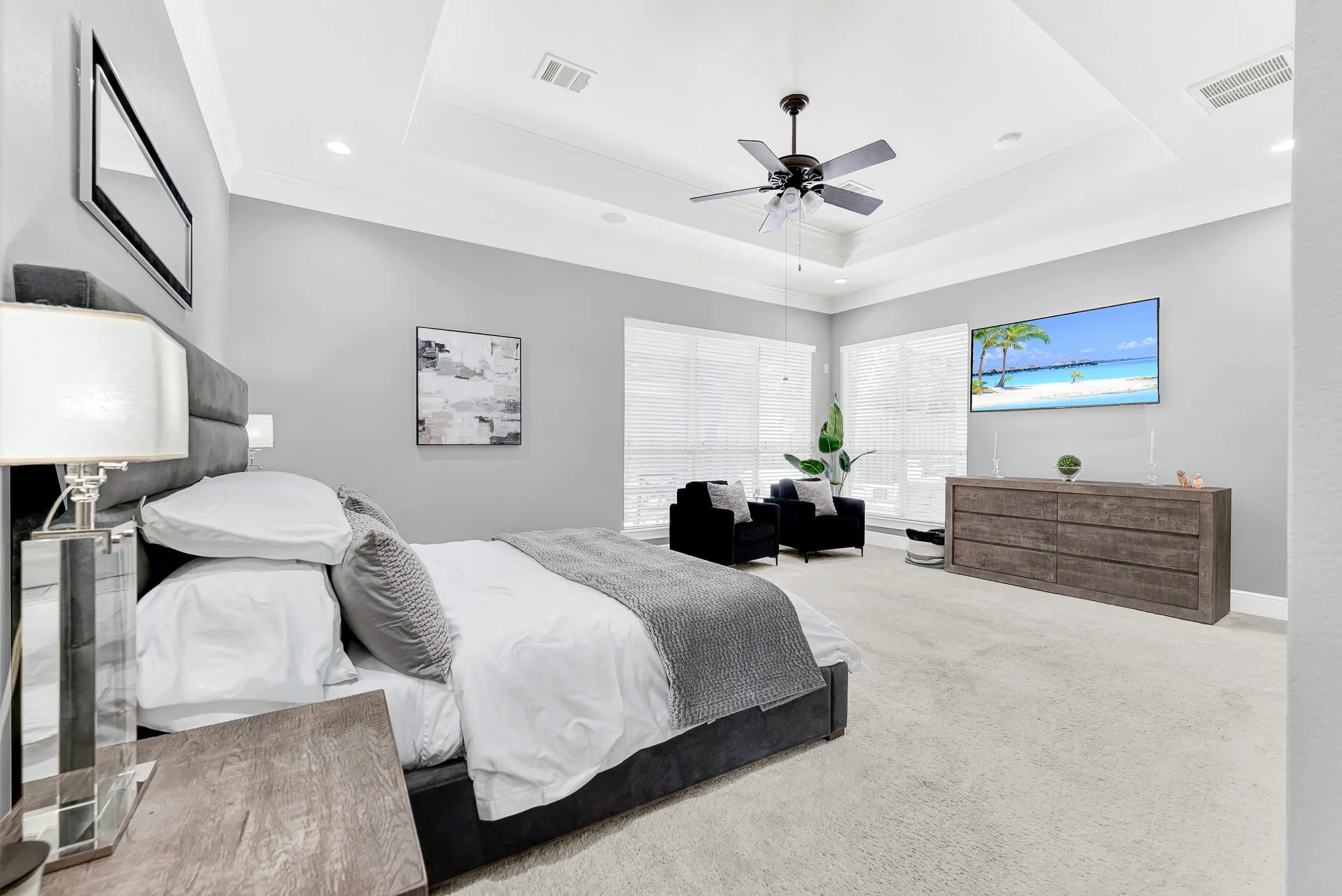 An impressive wall of updated windows illuminates the soft plush carpeting and high architectural ceilings of this primary retreat. Wake up to beautiful morning sunshine and enjoy quiet evenings watching your favorite show in comfort
