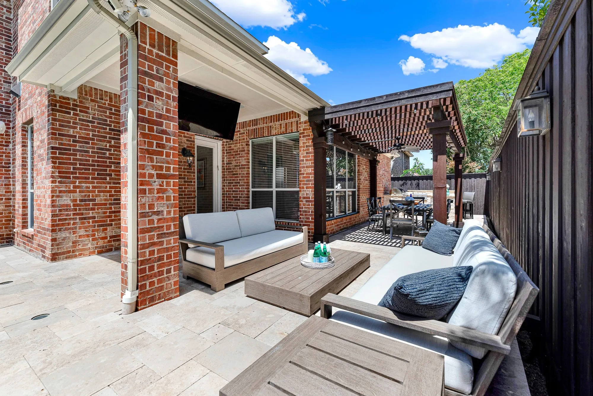 A custom 65" TV swings down from the ceiling above travertine stone decking on this covered patio. Catch game-day broadcasts or host movie nights outdoors with family and friends. TV can also be electronically rotated to face the pool!